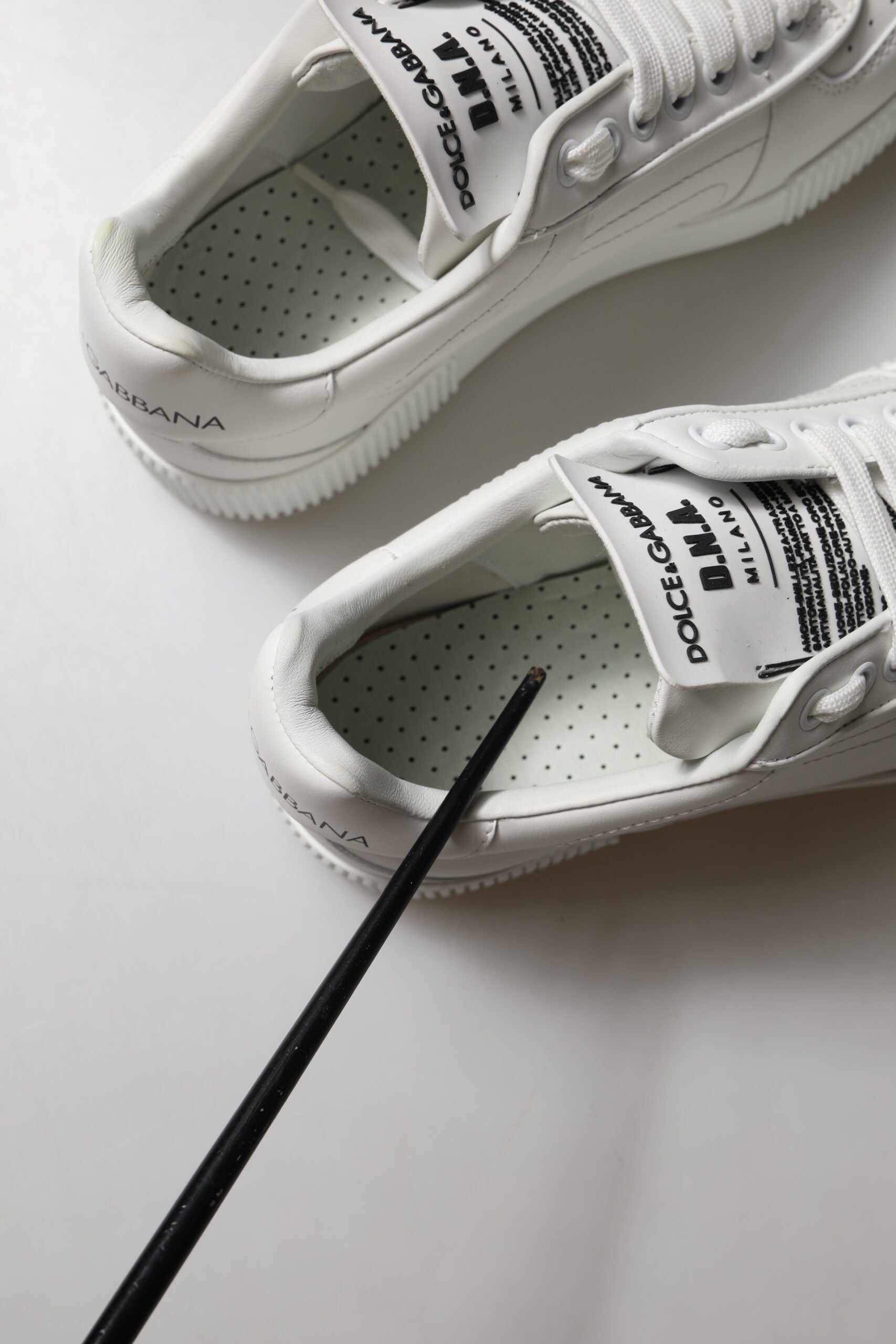 Pair of white leather sneakers with black laces and logo, featuring low top design