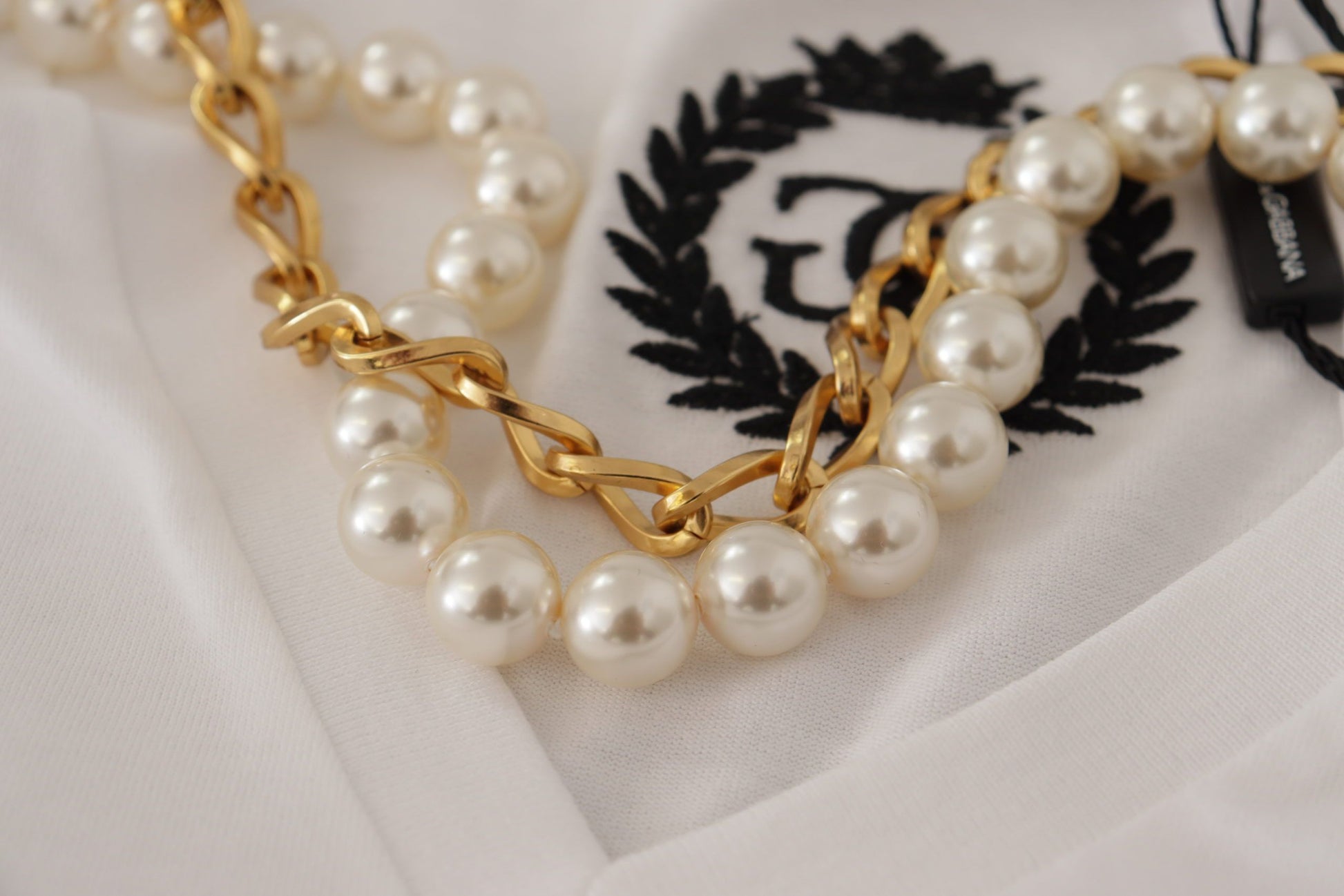 Gold pearl necklace on white fabric