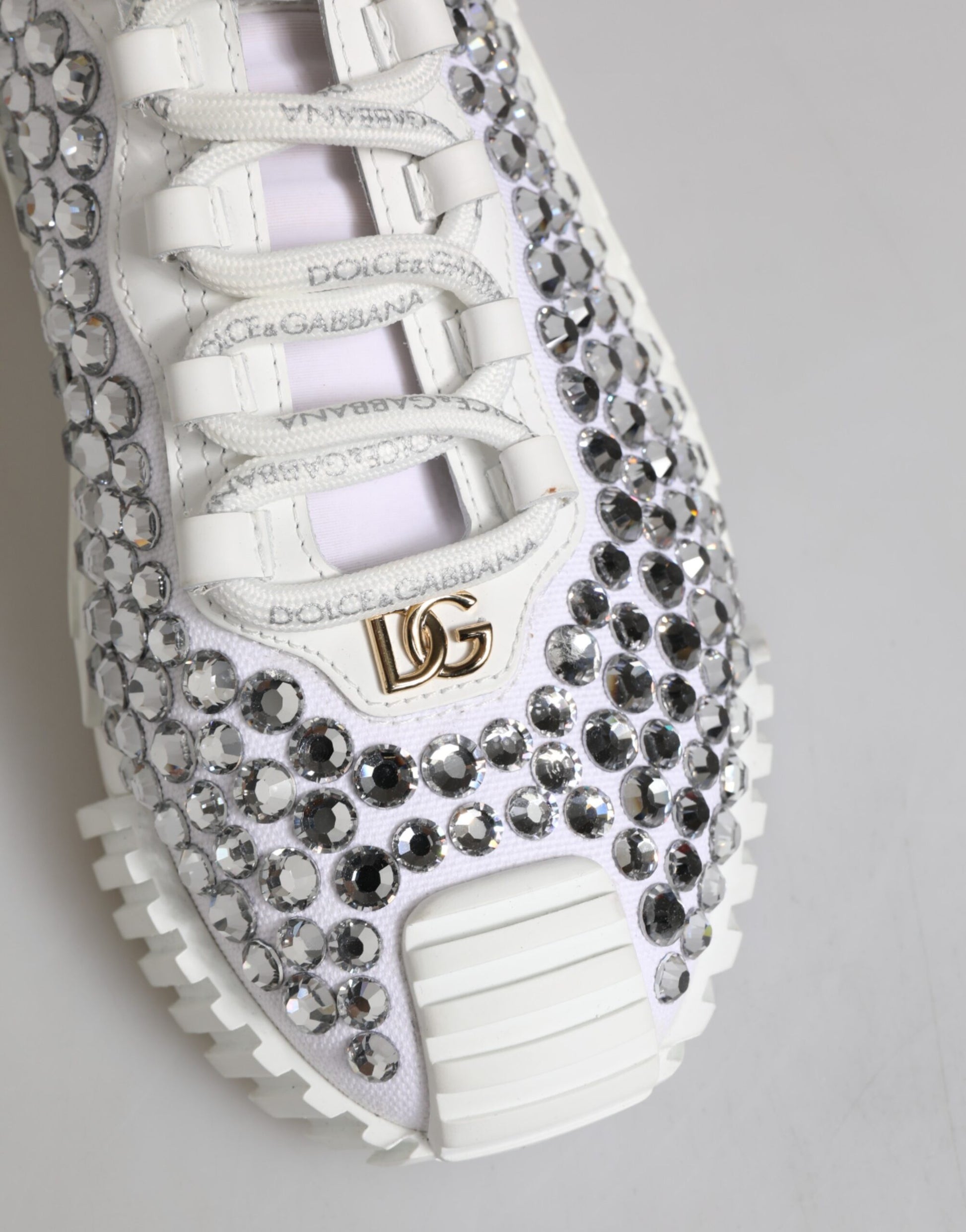 White sneakers with embellishments, featuring a logo on the side