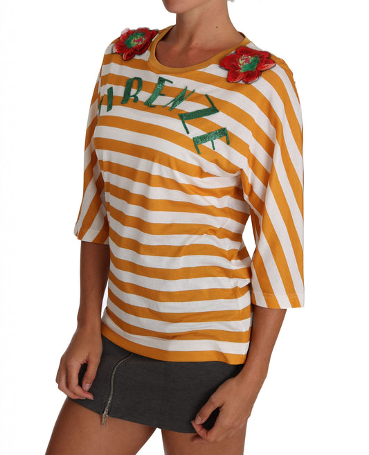 Woman wearing yellow striped sweater with red flowers on sleeve