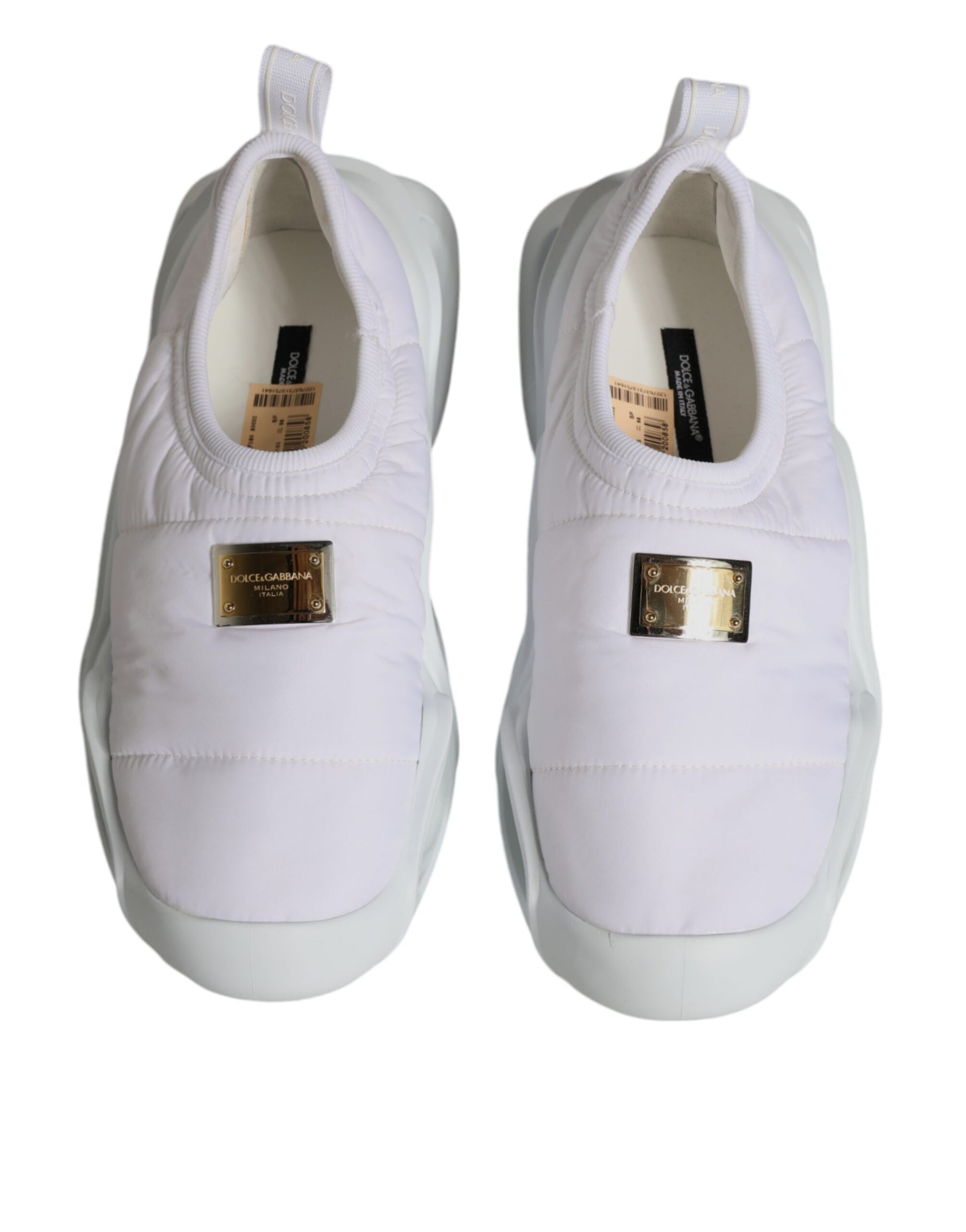 Pair of white sneakers with gold accents and a tag on the tongue