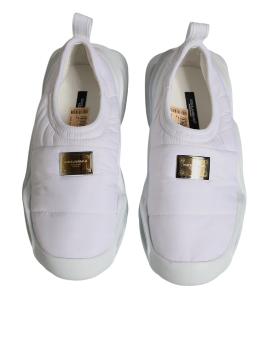 Pair of white sneakers with gold accents and a tag on the tongue