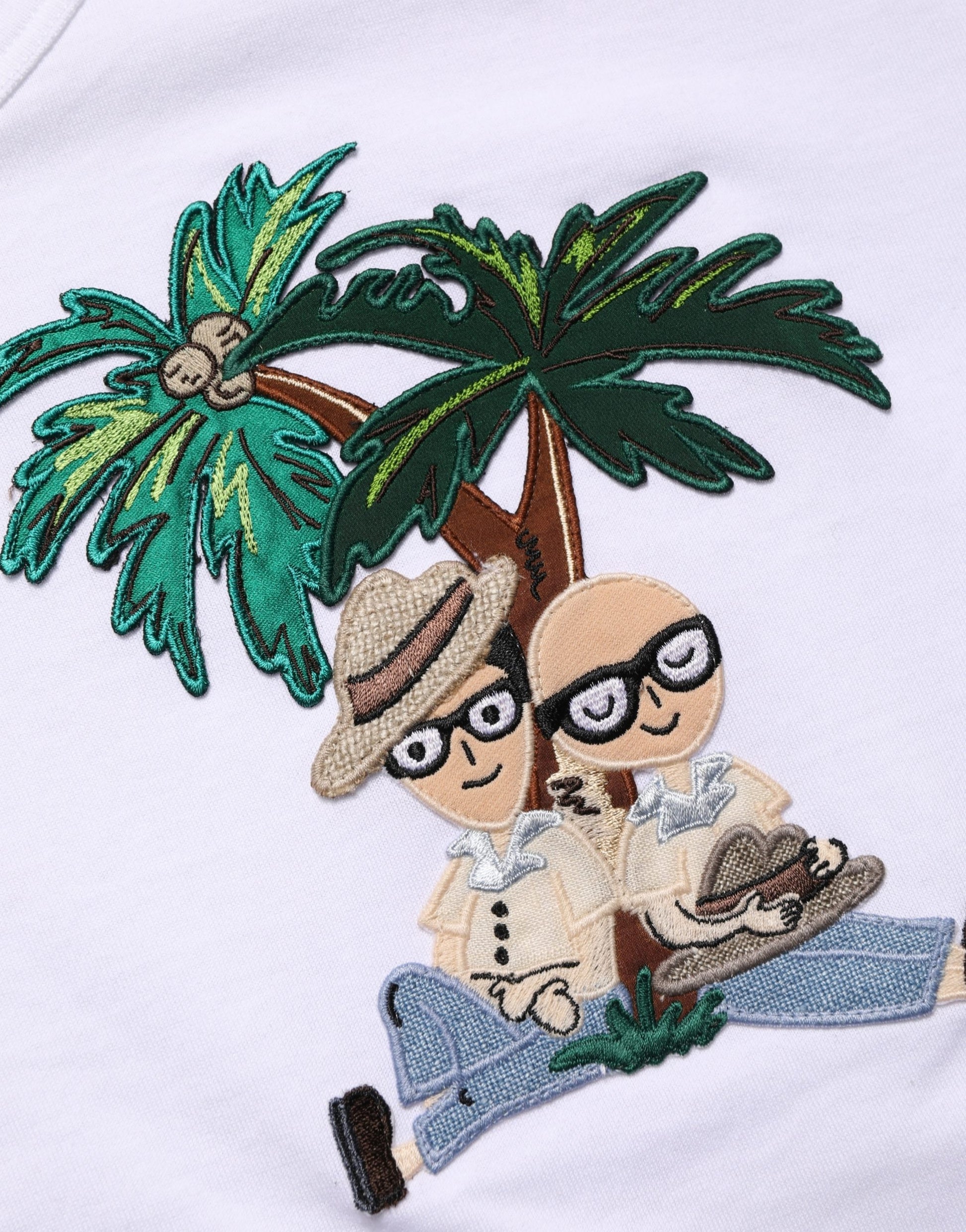 Embroidered design on shirt featuring two cartoon men sitting under a palm tree