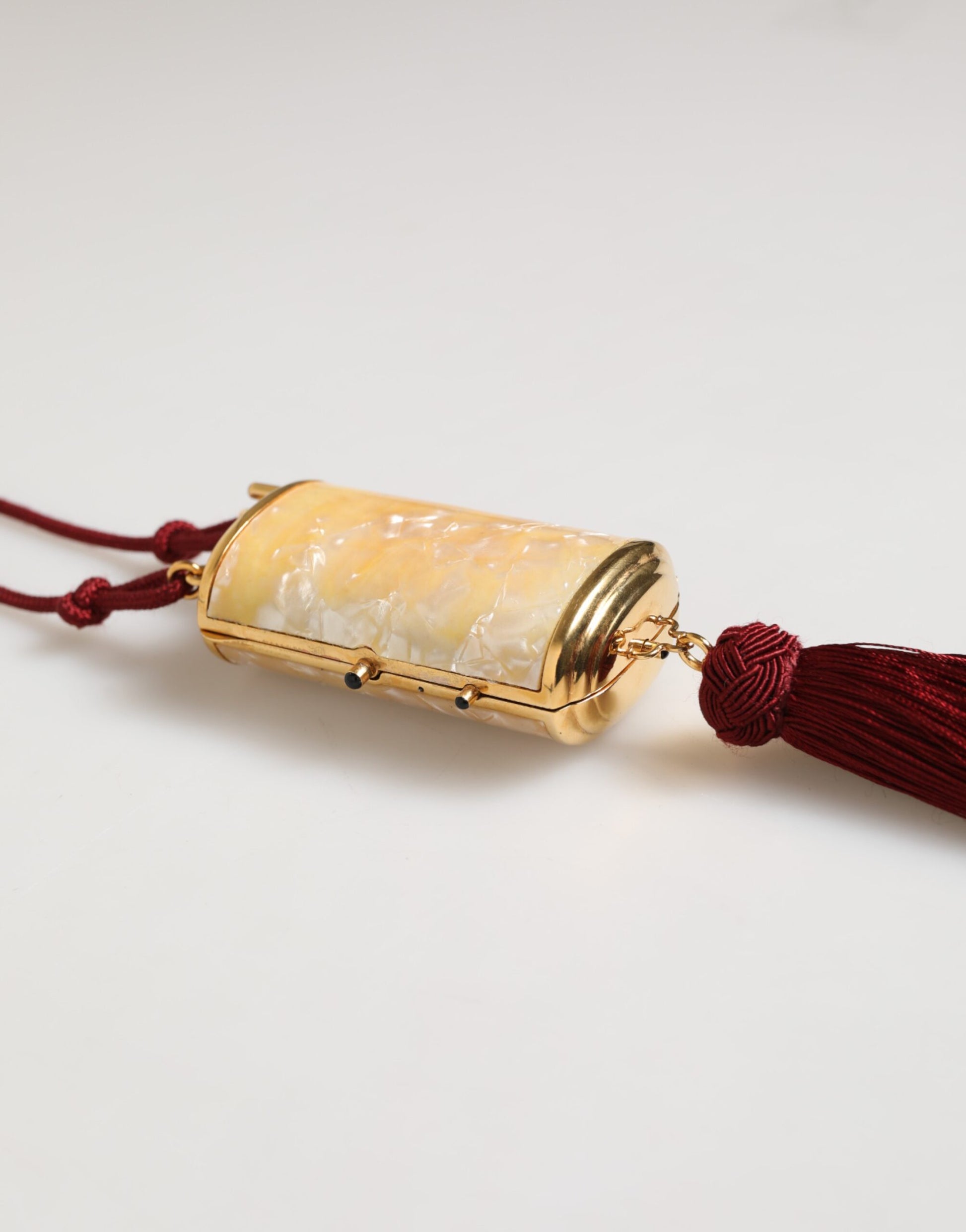 Small gold container with red tassel necklace
