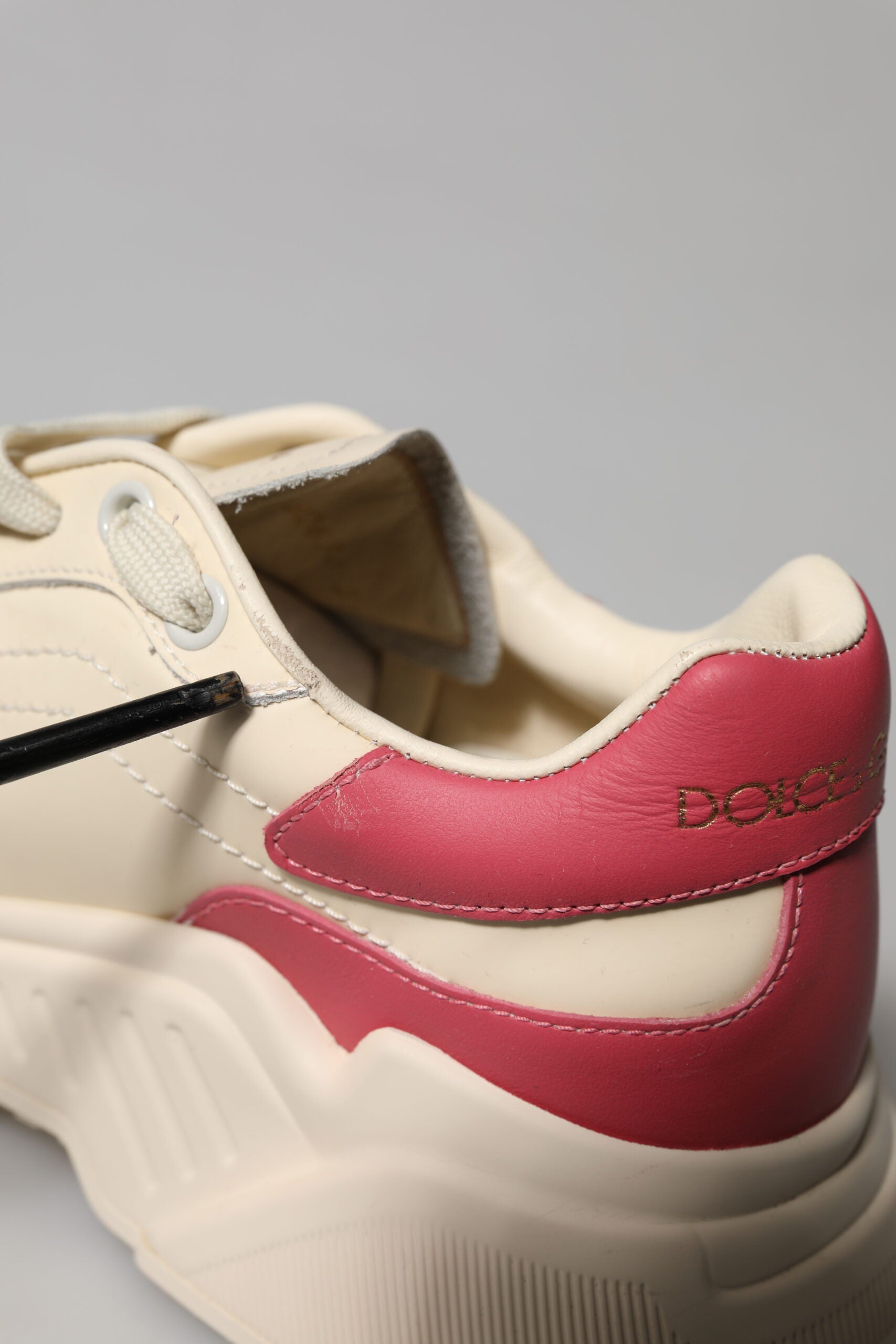 A pair of white pink leather sneakers with red accents, featuring the Dolce & Gabbana logo