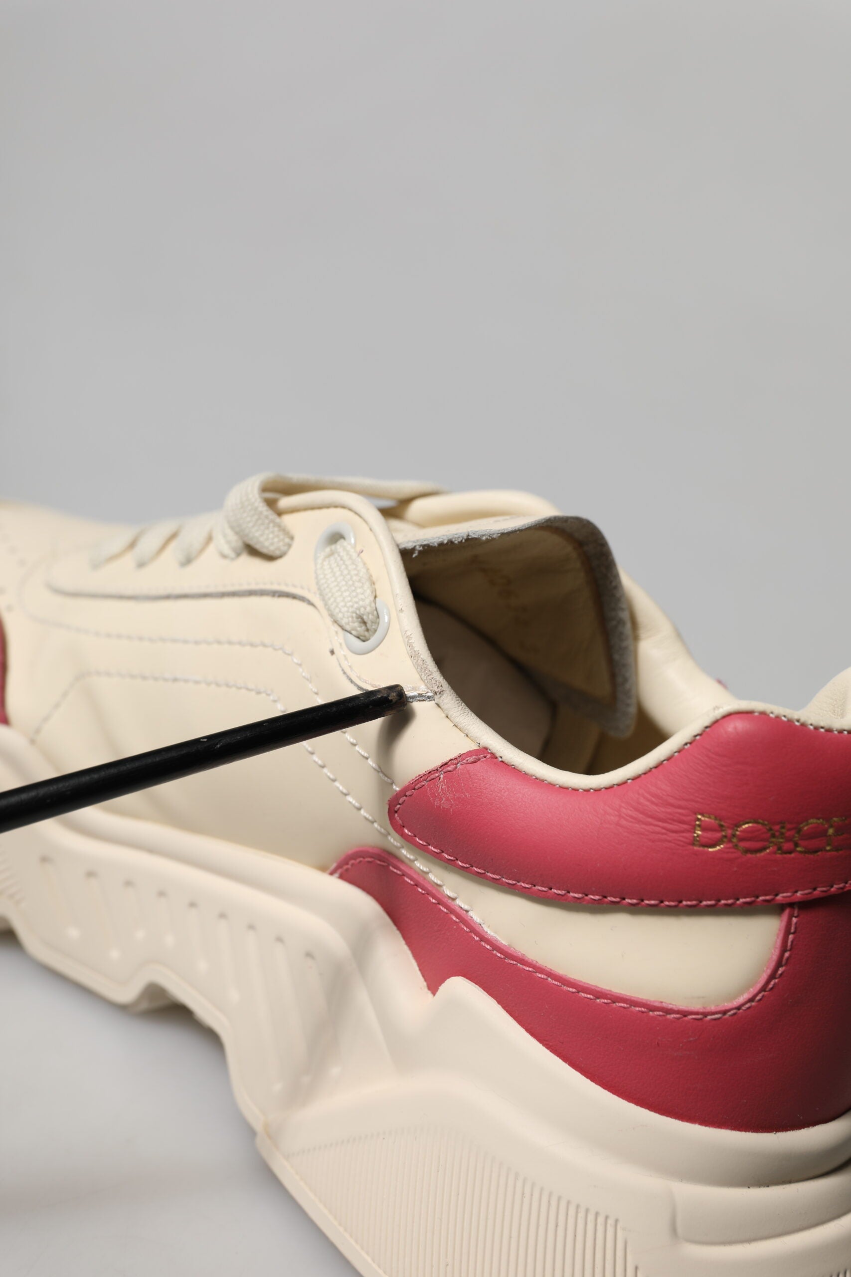 A pair of white pink leather sneakers with red accents, featuring a black Nike swoosh logo