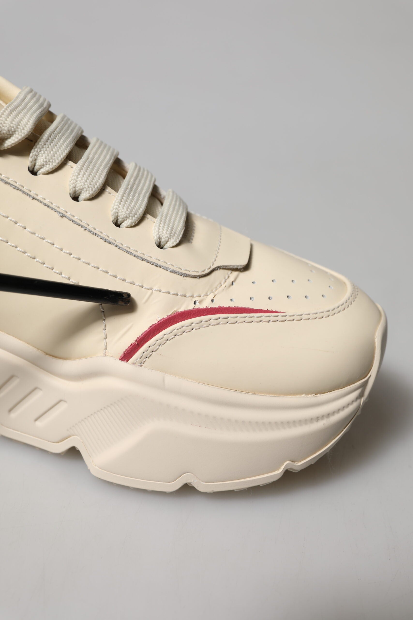 A pair of white pink leather sneakers with red accents and a black sole