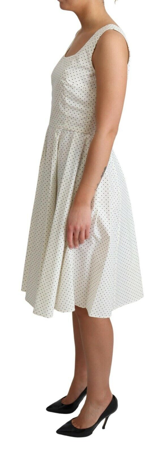 A white polka dotted cotton dress with a fitted bodice and flared skirt
