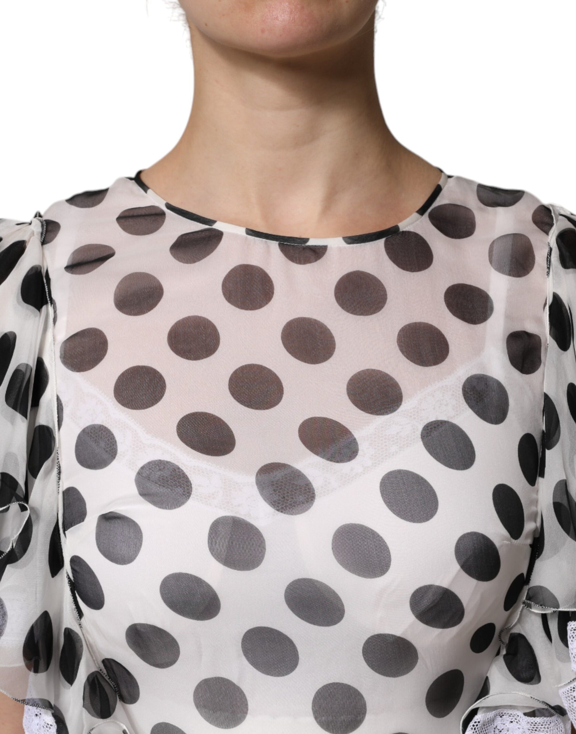 A woman wearing a white polka dotted dress with a silk blend fabric. The dress features an A-line cut and is