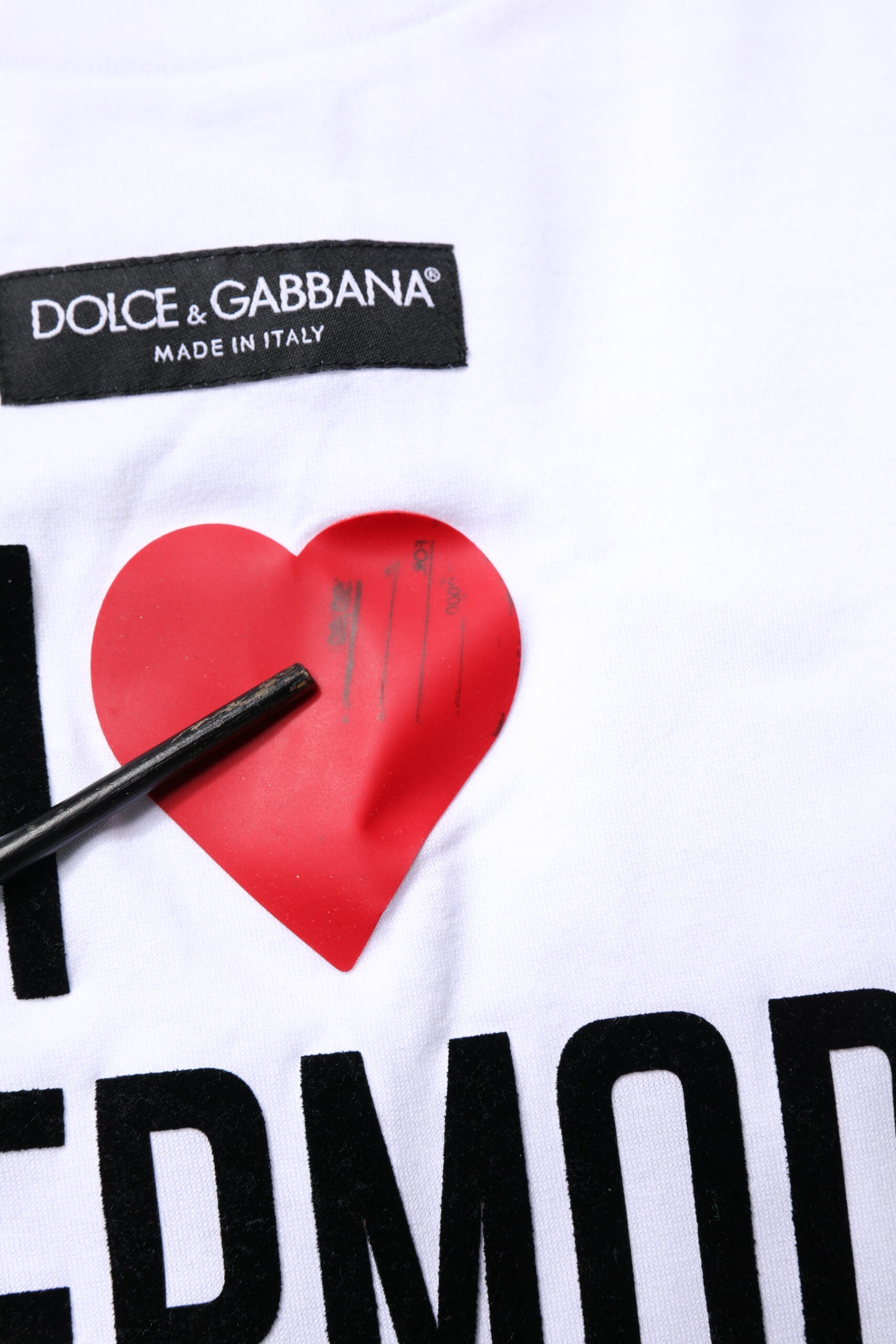 White t-shirt with red heart graphic and black writing