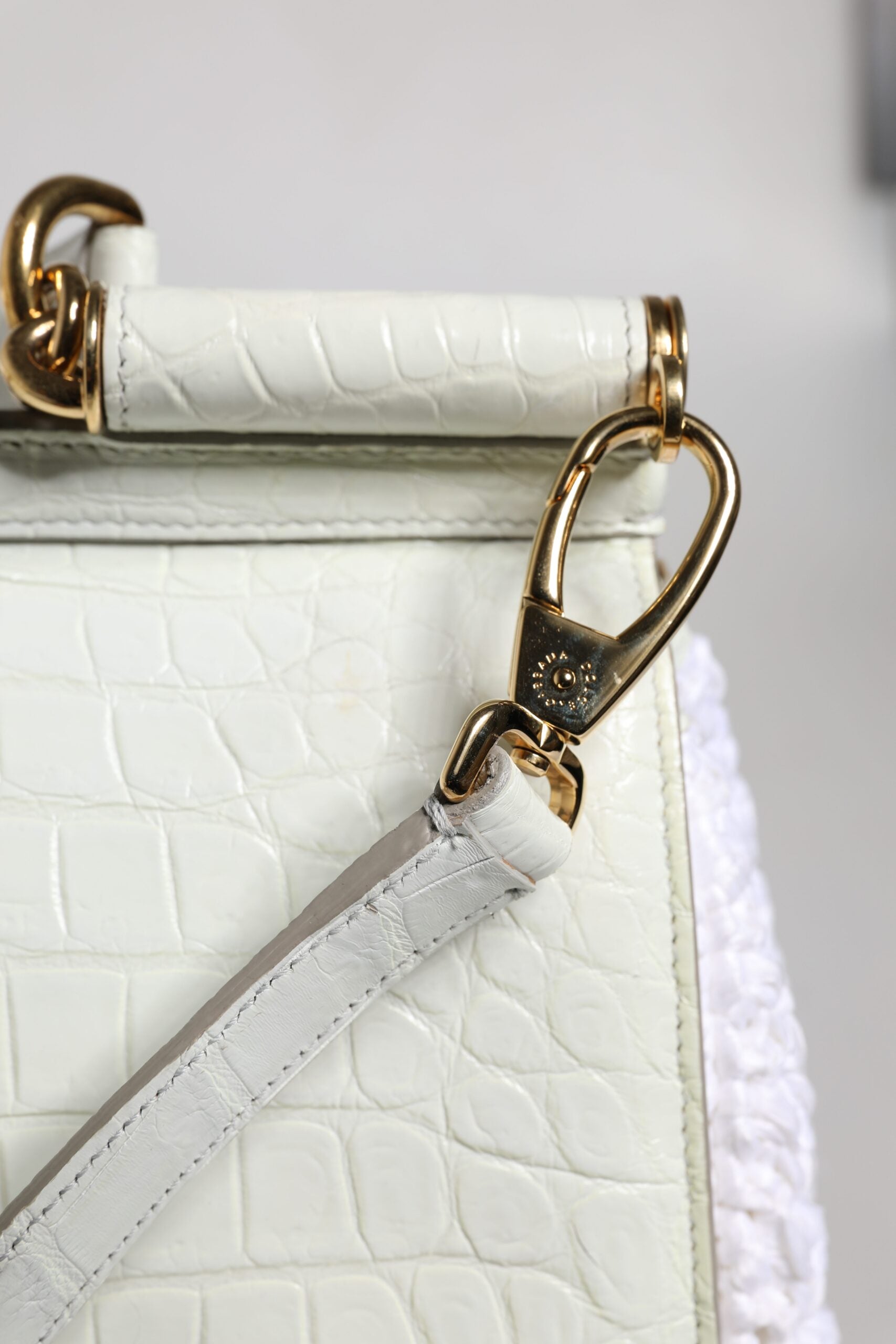 Gold zipper pull on a white leather purse