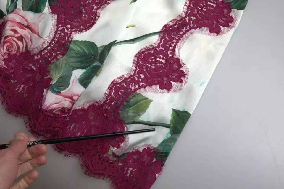 Hand holding a black pen over a piece of fabric with lace and floral designs