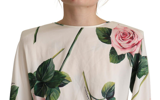 A long sleeve dress with a white rose print and green leaves on a cream background