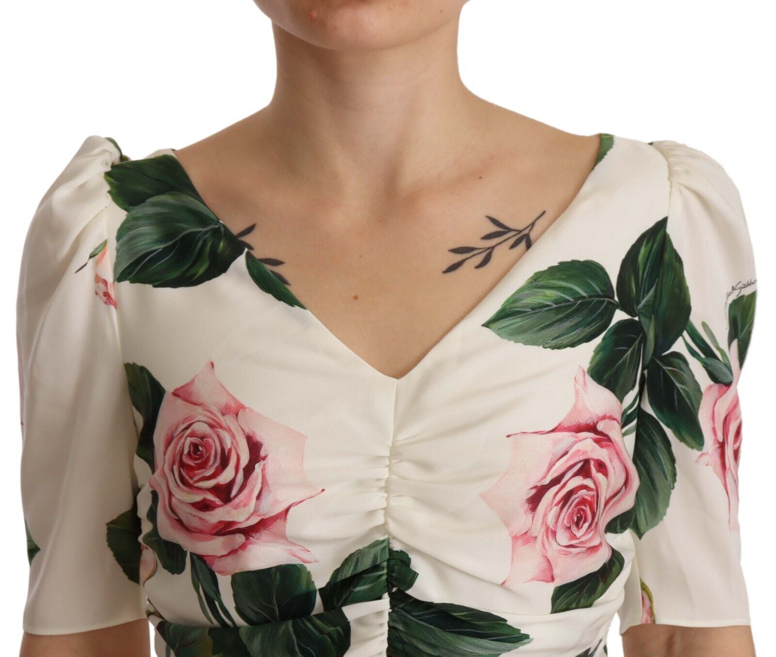 A white dress with a floral print featuring pink roses and green leaves on the bodice