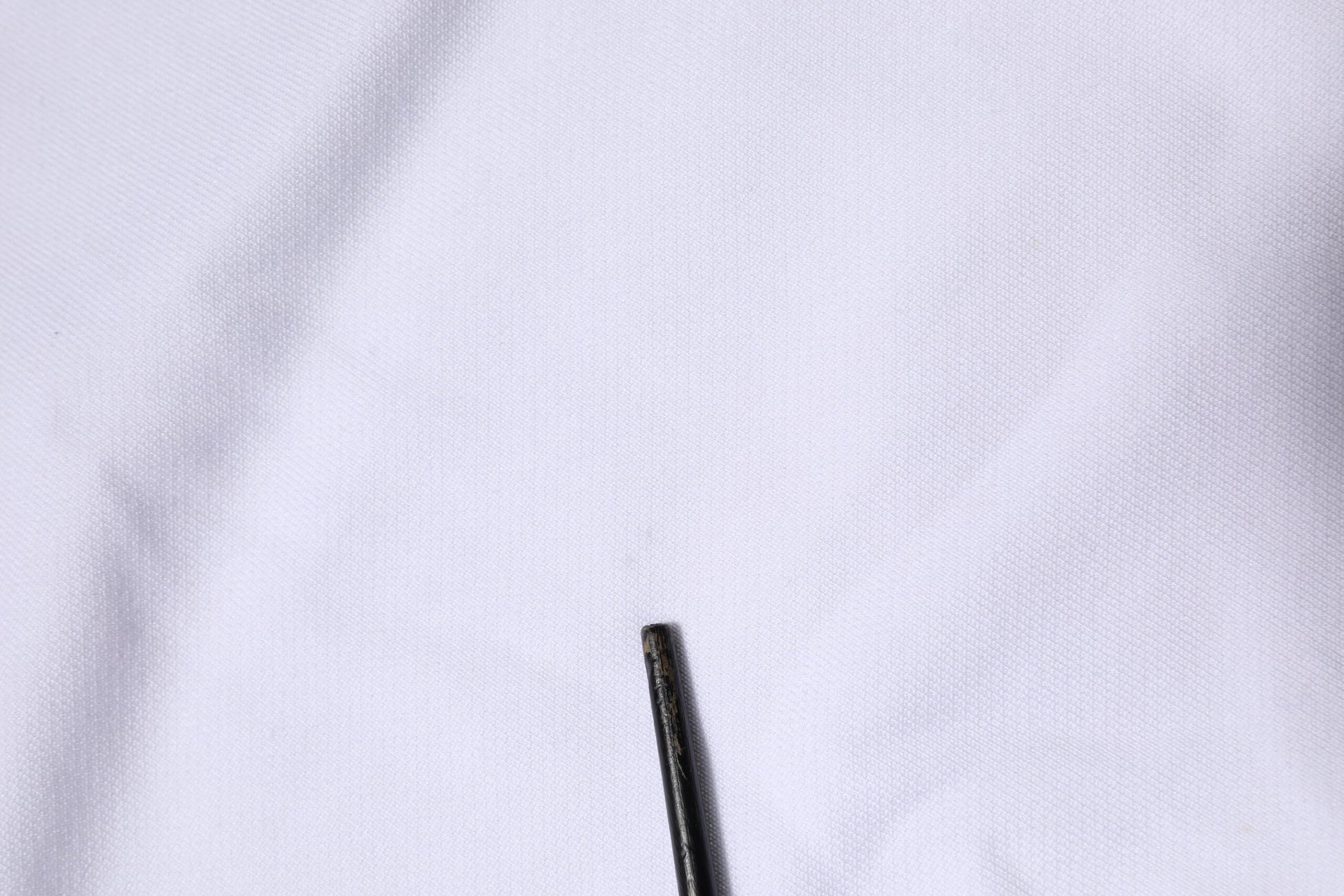 Black sewing needle on white fabric