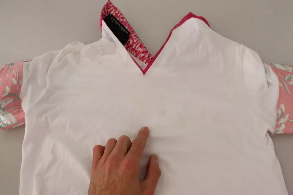 Man's hand touching white shirt on table