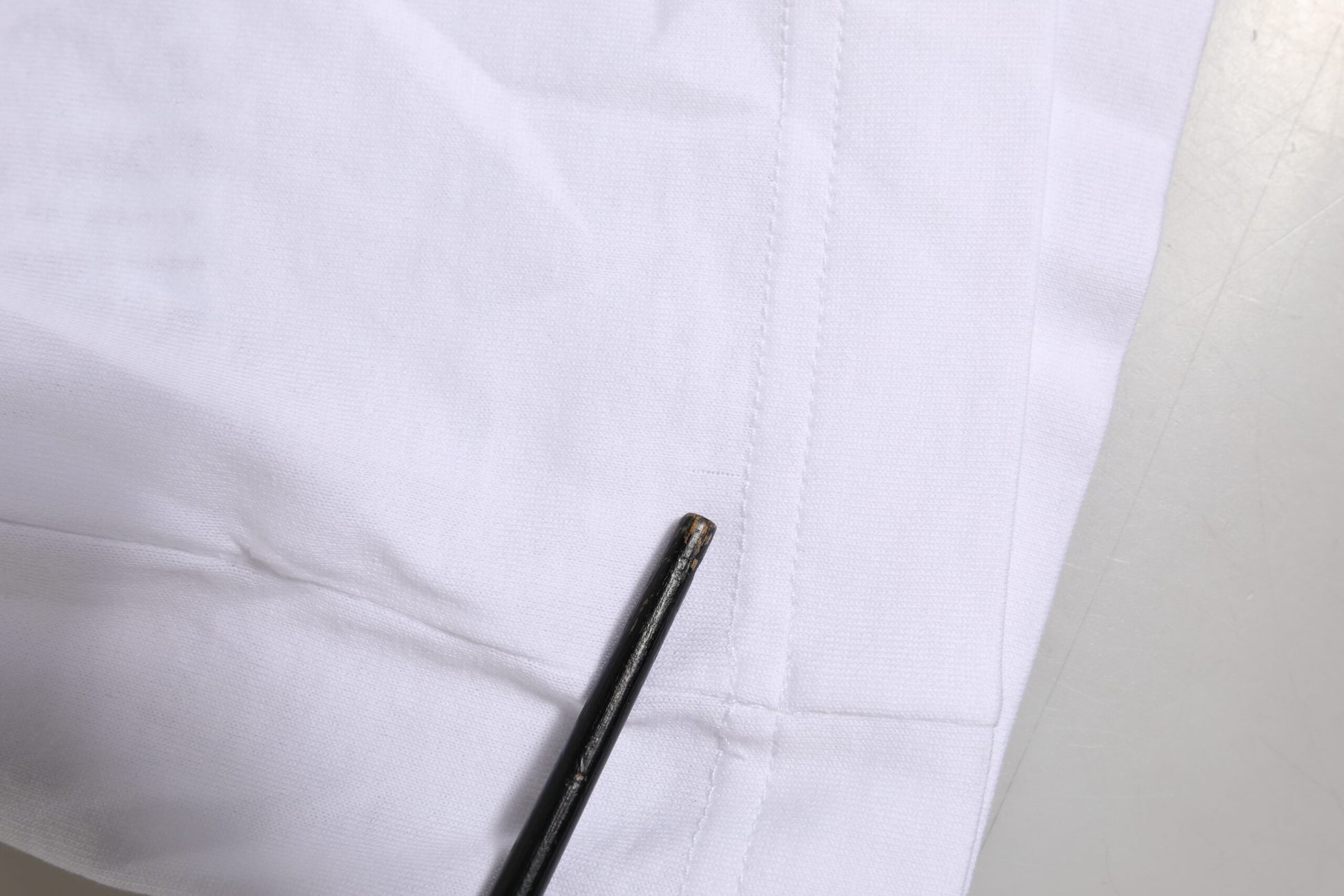 Black sewing needle on white fabric