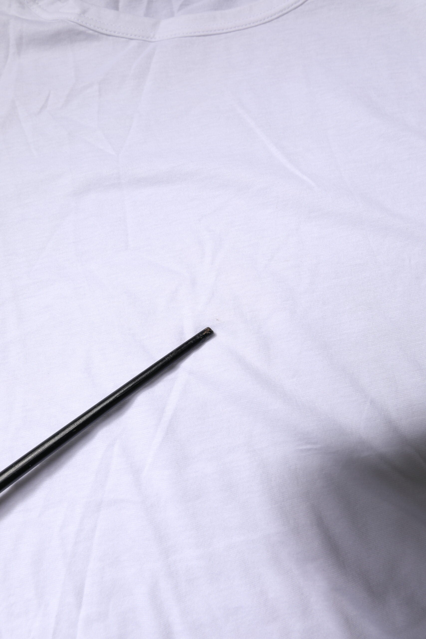 White t-shirt on a table with a black pen resting on it