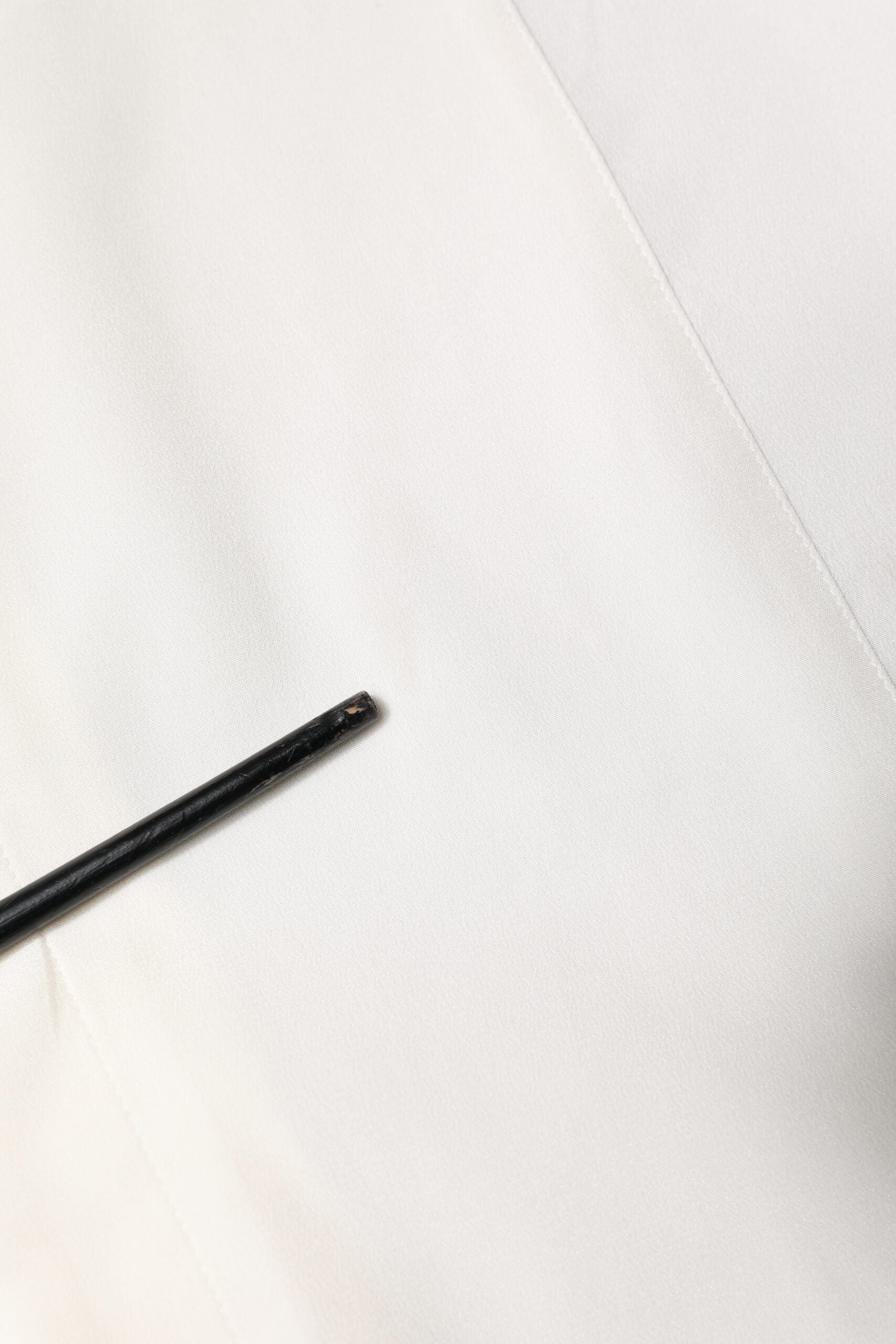 A black pencil on a white silk dress shirt with gold accents