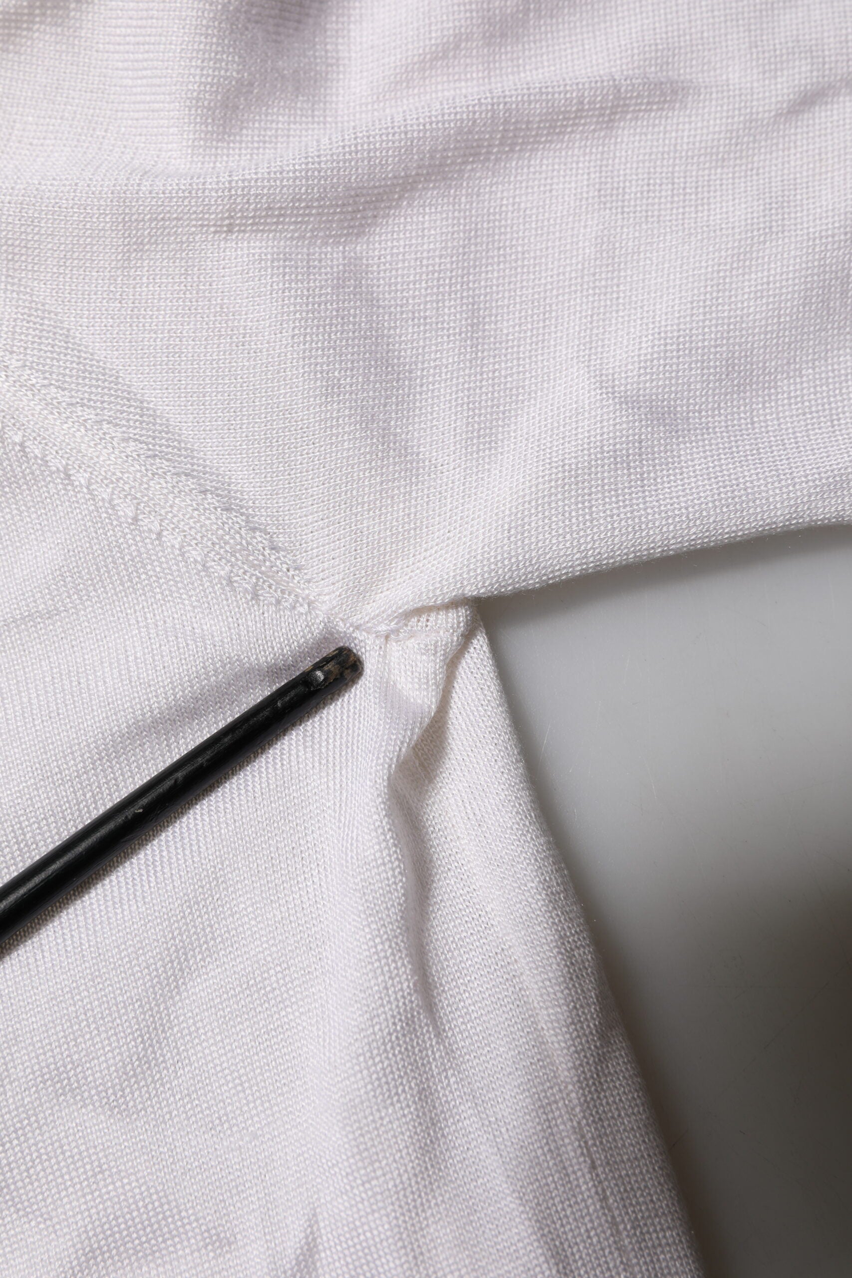 White fabric with a black thread stitched on it