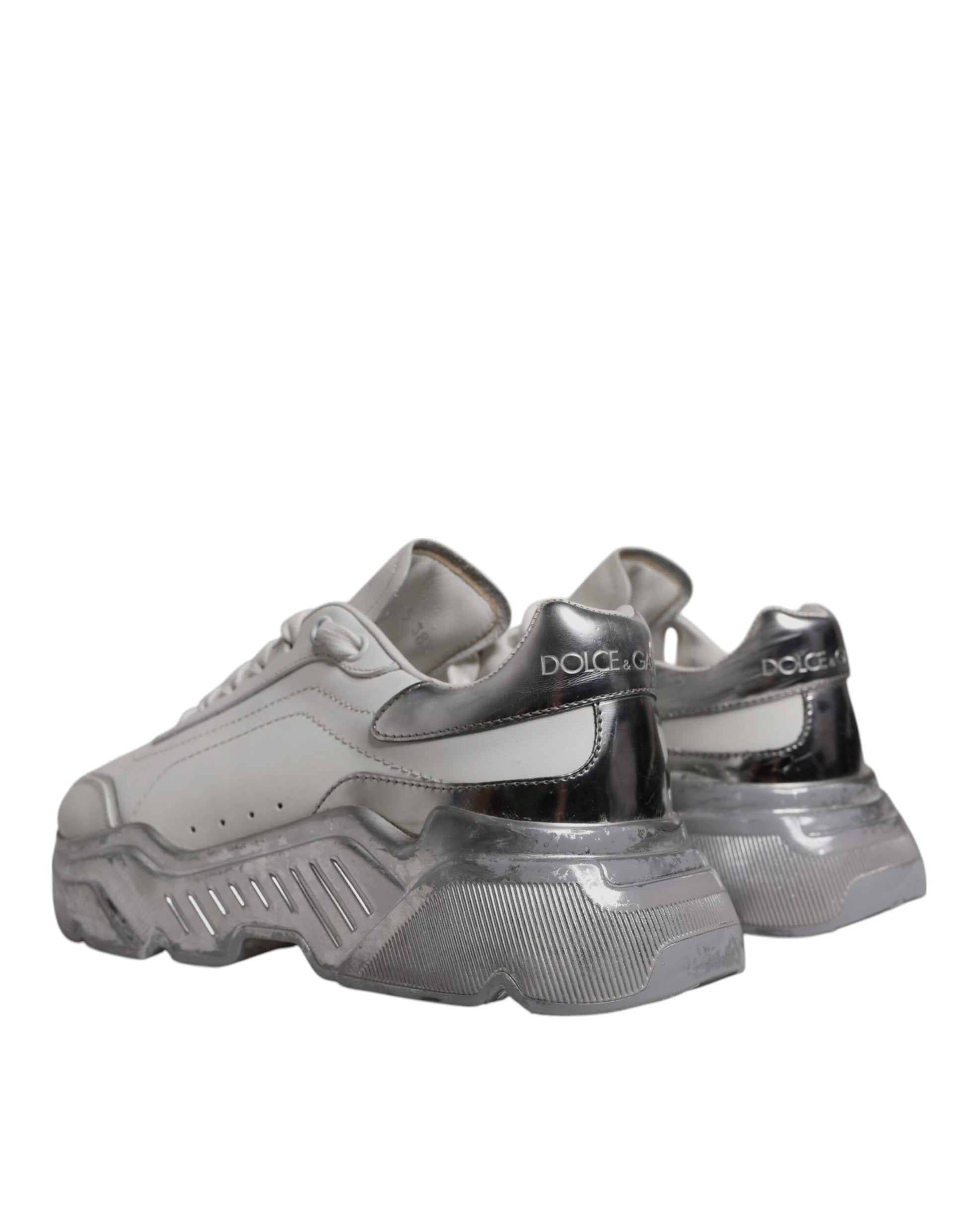 A pair of white and silver sneakers with black laces, featuring the Dolce & Gabbana logo