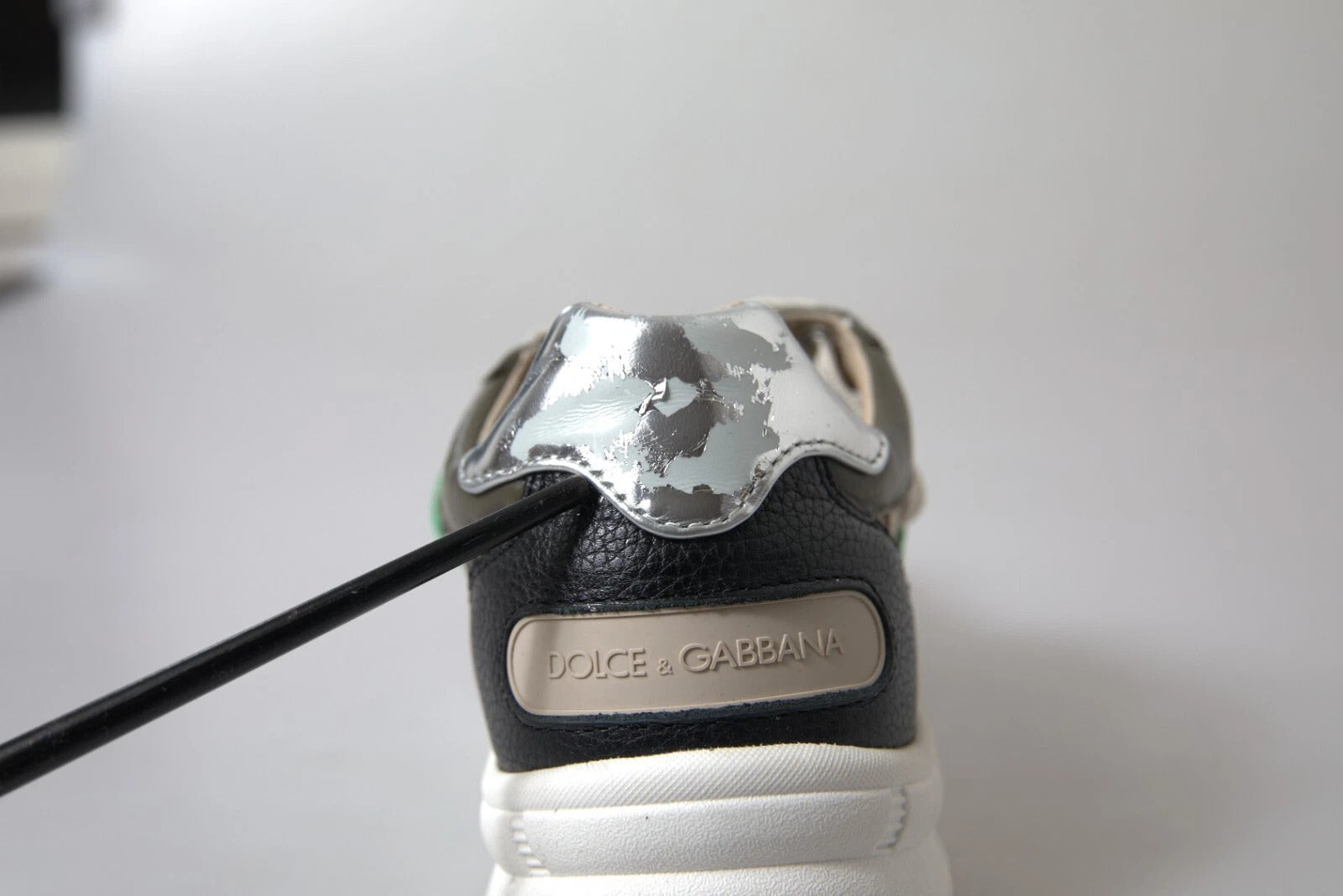 A pair of white and silver leather sneakers with a logo on the side, featuring a lace-up design