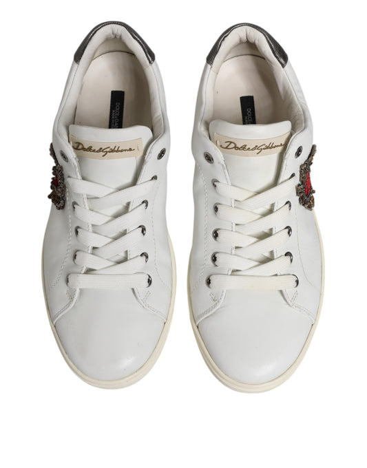 Pair of white sneakers with silver accents, featuring a sacred heart logo on the side