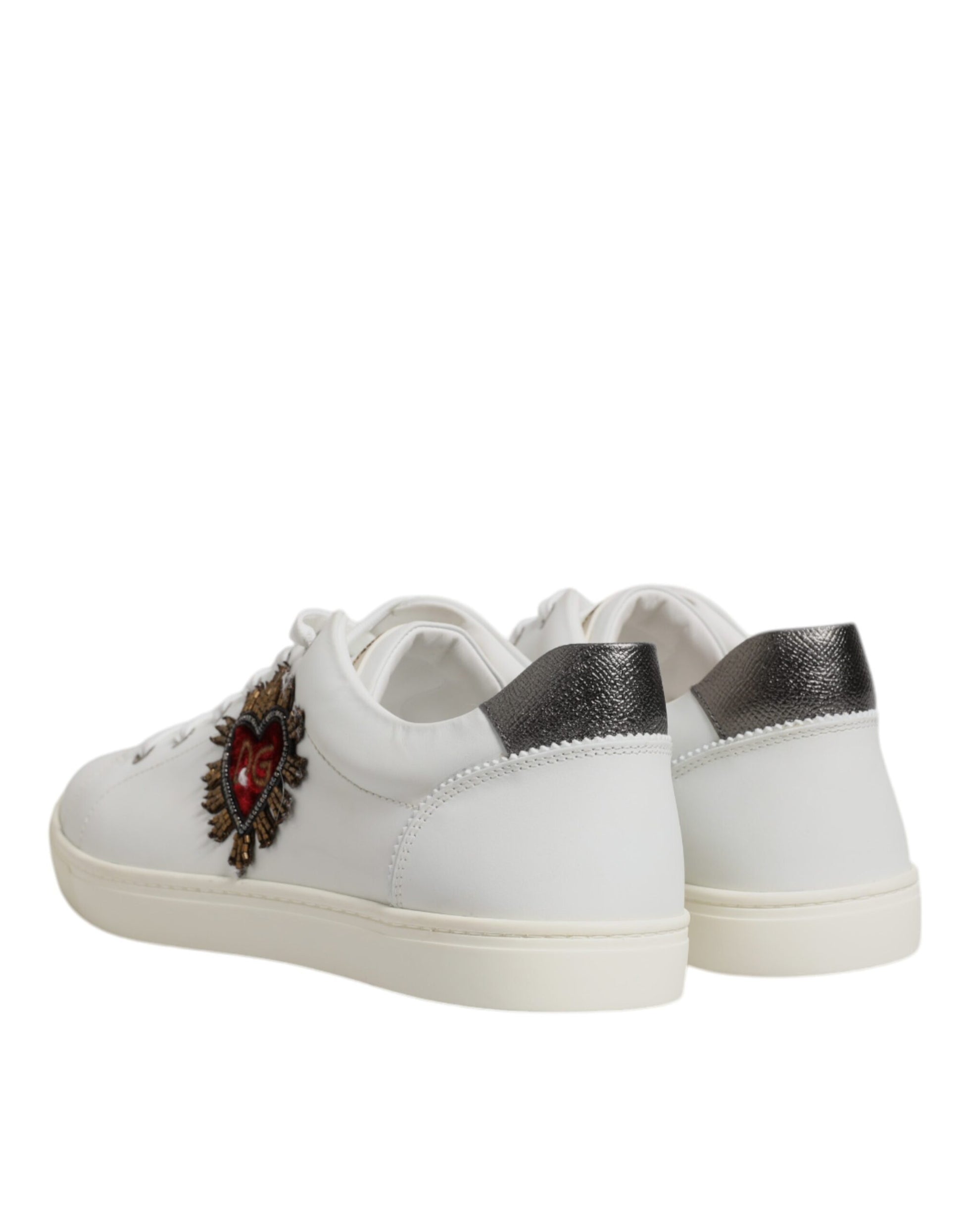 A pair of white sneakers with a silver sacred heart design on the side