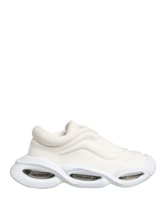 A pair of white slip-on shoes with a low top, featuring a wave design on the sole