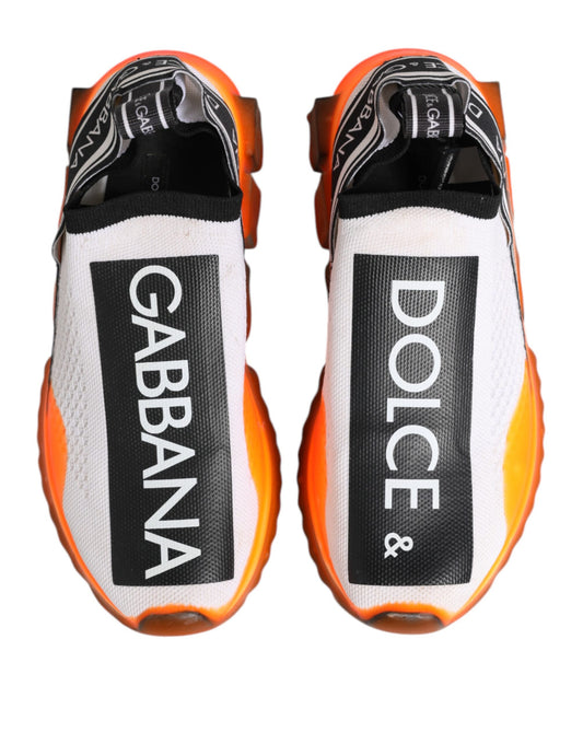 Pair of white slip-on shoes with black and orange accents, featuring the brand names Dolce & Gabbana