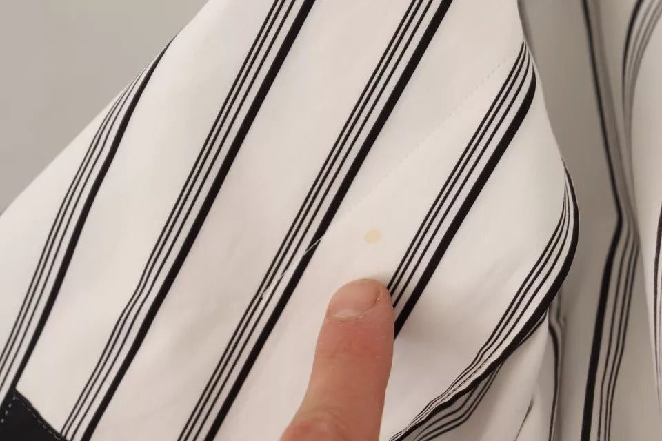 A person's hand pointing at a piece of clothing with vertical stripes