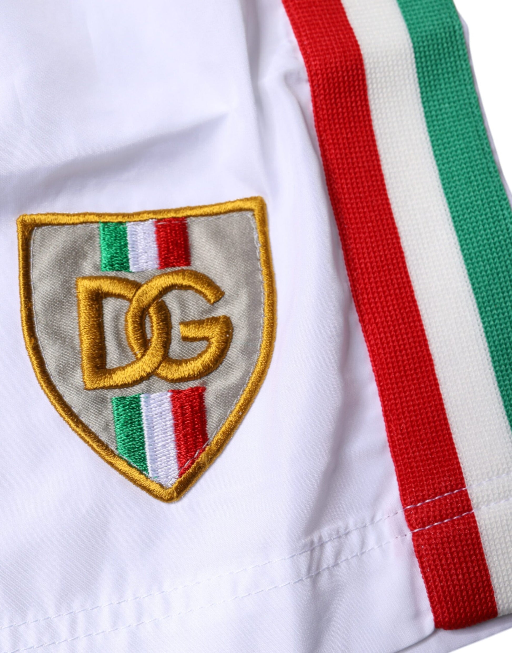 A pair of white and red striped beachwear shorts with a gold logo