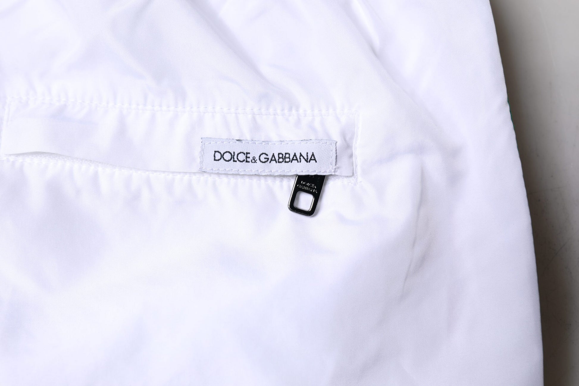 White swim shorts with stripe pattern, branded label on waistband