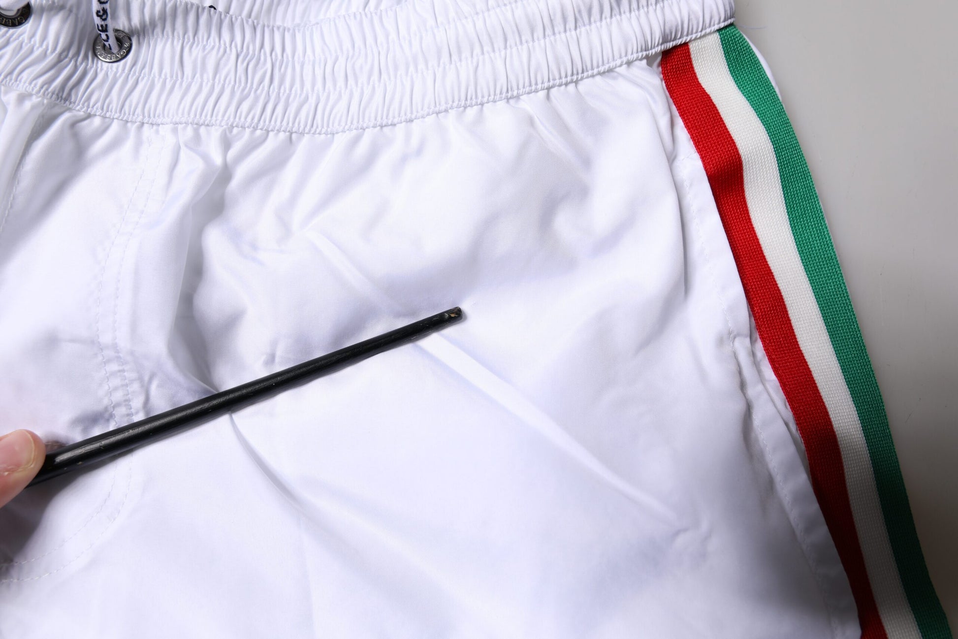 A pair of white and red striped beach shorts with a black zipper