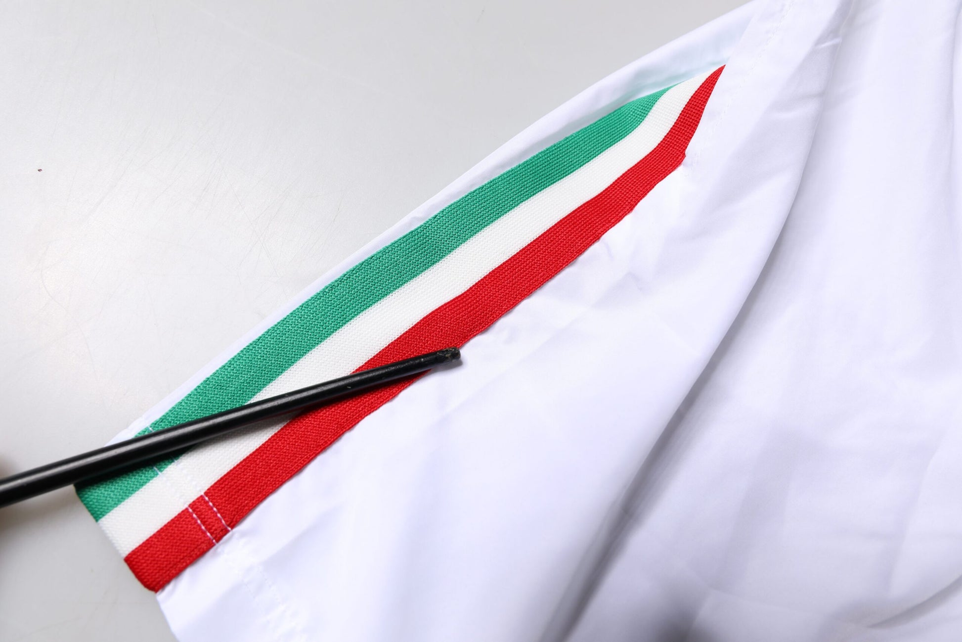 A pair of white swim shorts with red and green stripes