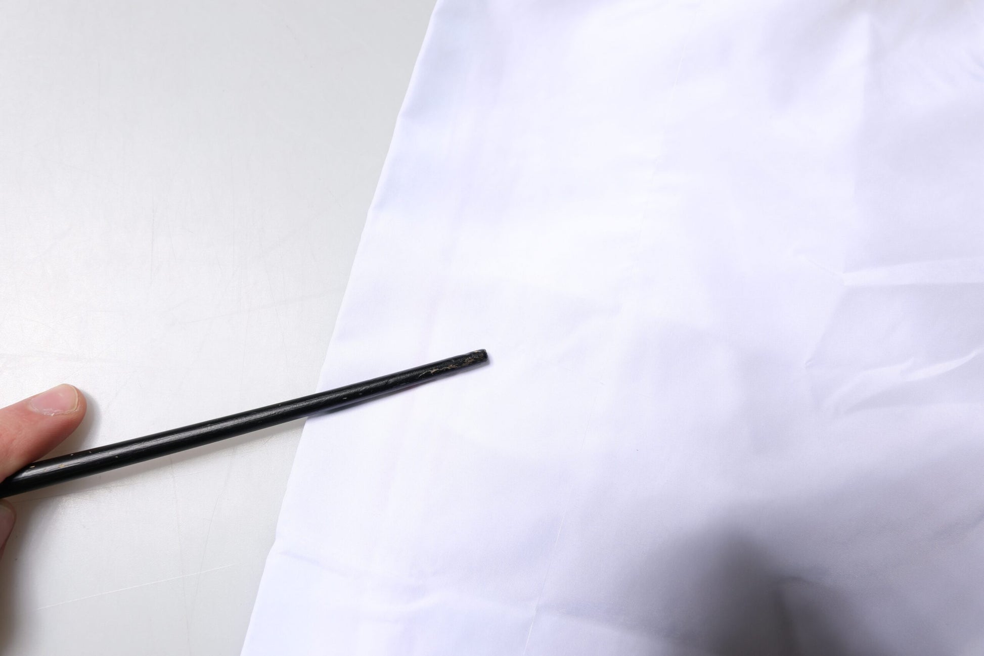 Hand holding black pen over white paper with beachwear shorts