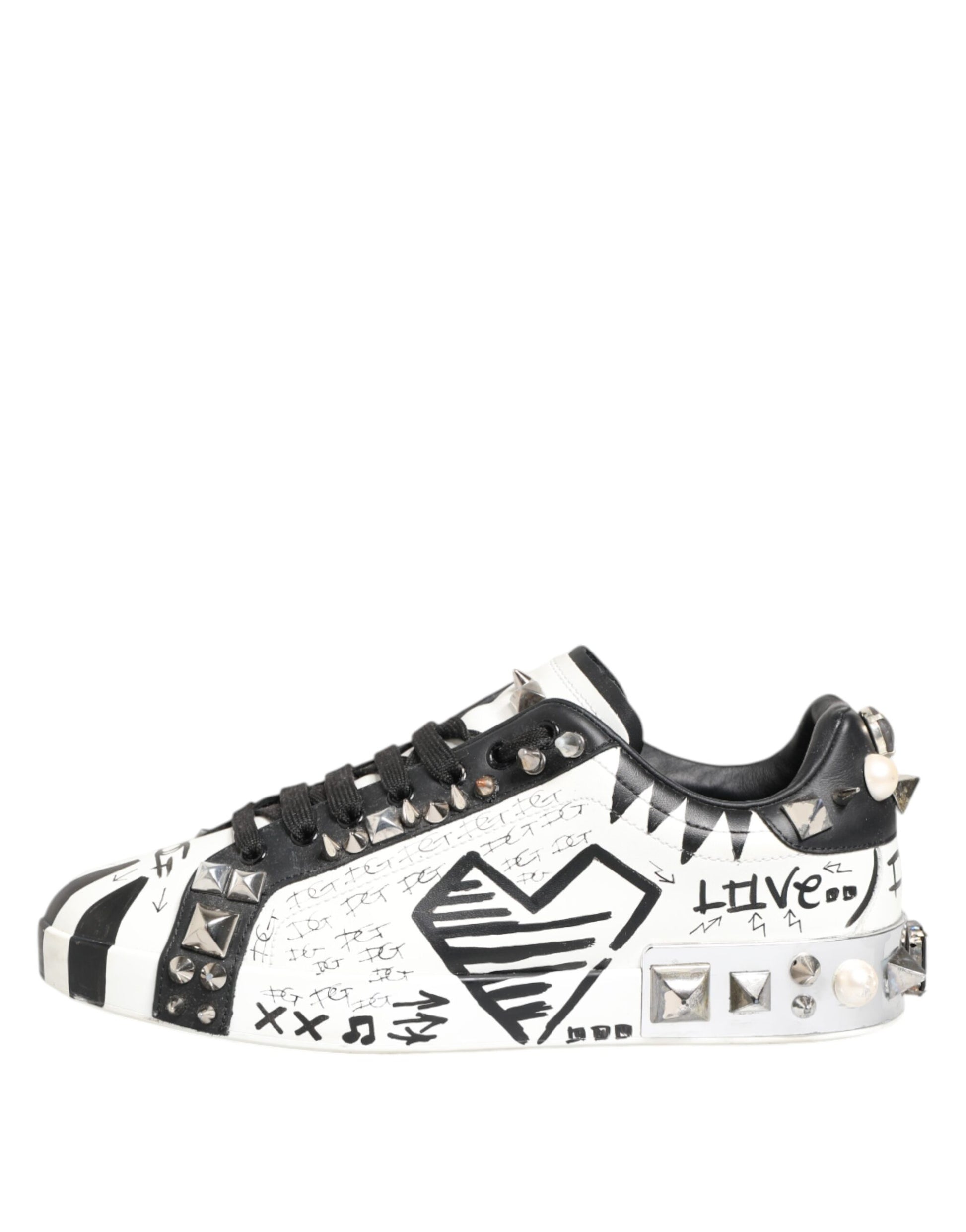 A pair of white sneakers with black studs and a printed design on the side, featuring the word "LOVE" in bold letters