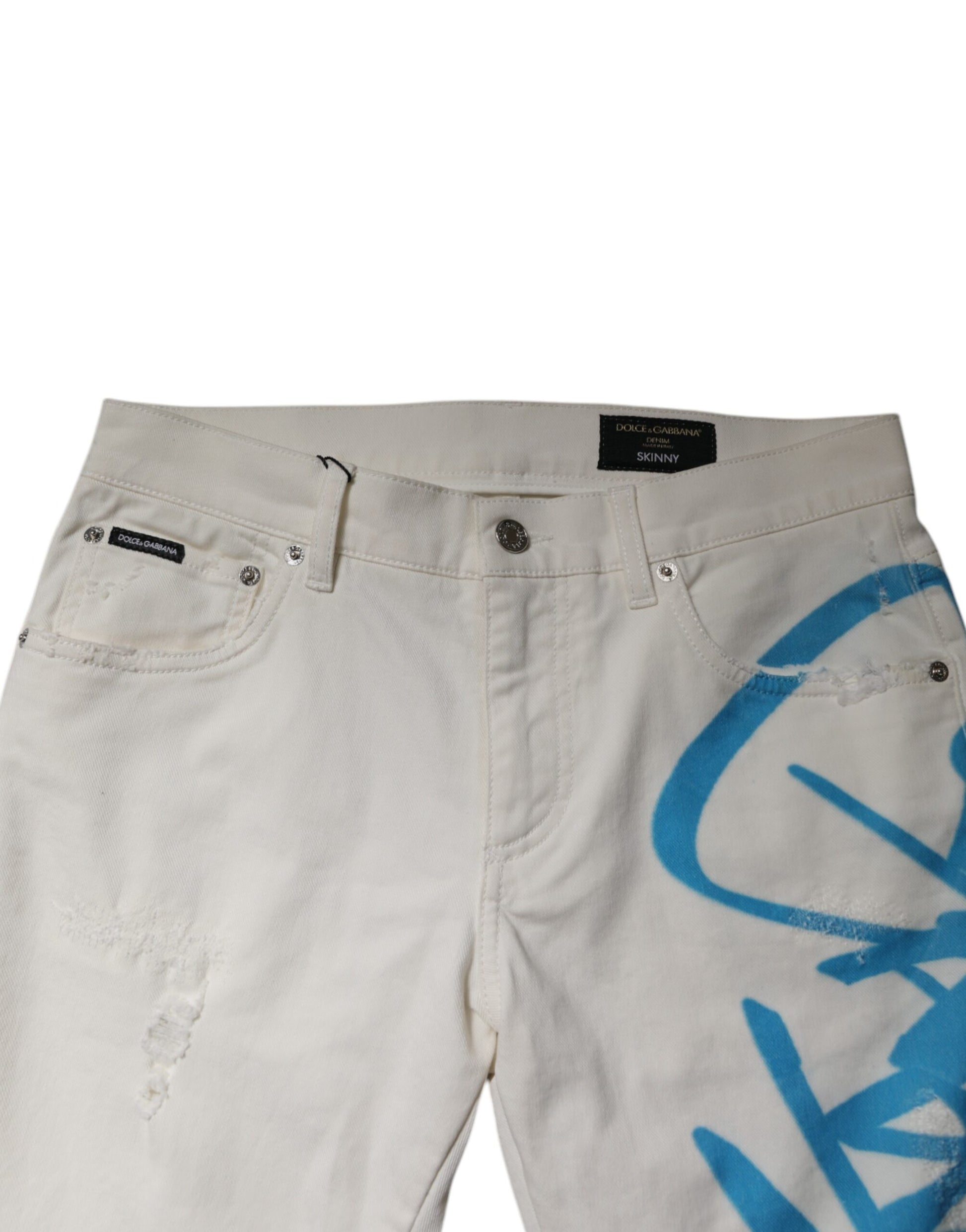Pair of light wash denim shorts with distressed details and blue graffiti design on right leg
