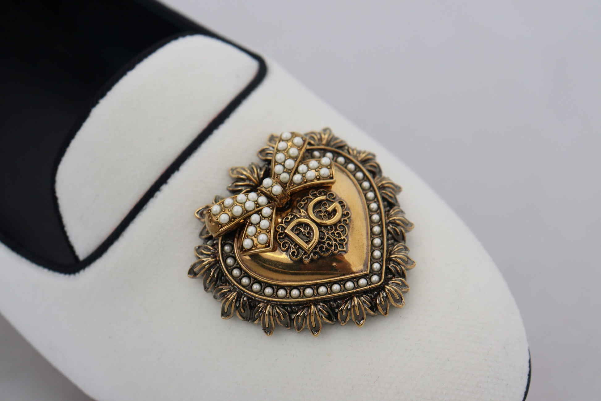 Pair of black and white shoes with a heart shaped brooch on one shoe