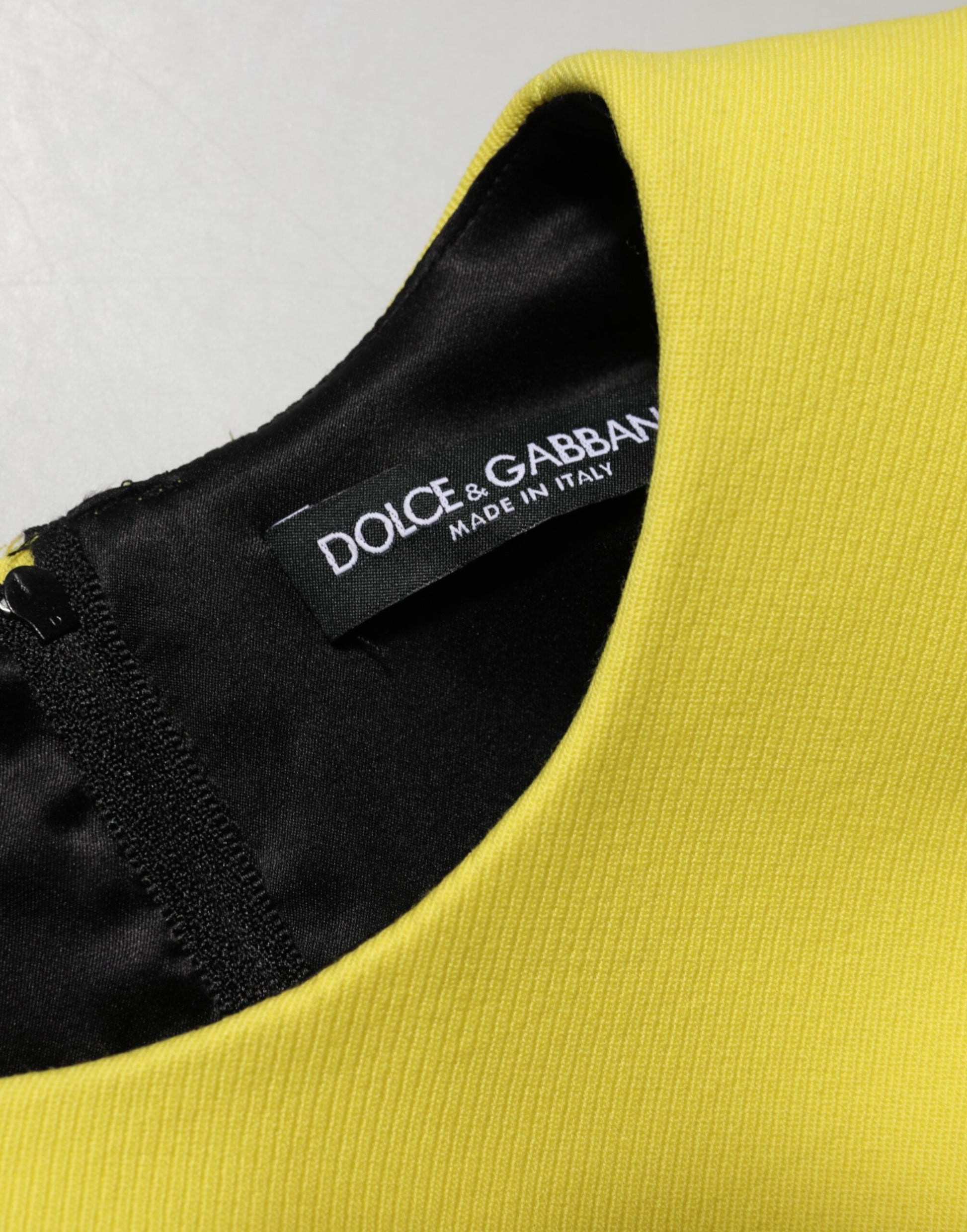 Yellow sleeveless mini dress with black trim and a label that reads "Dolce & Gabbana"