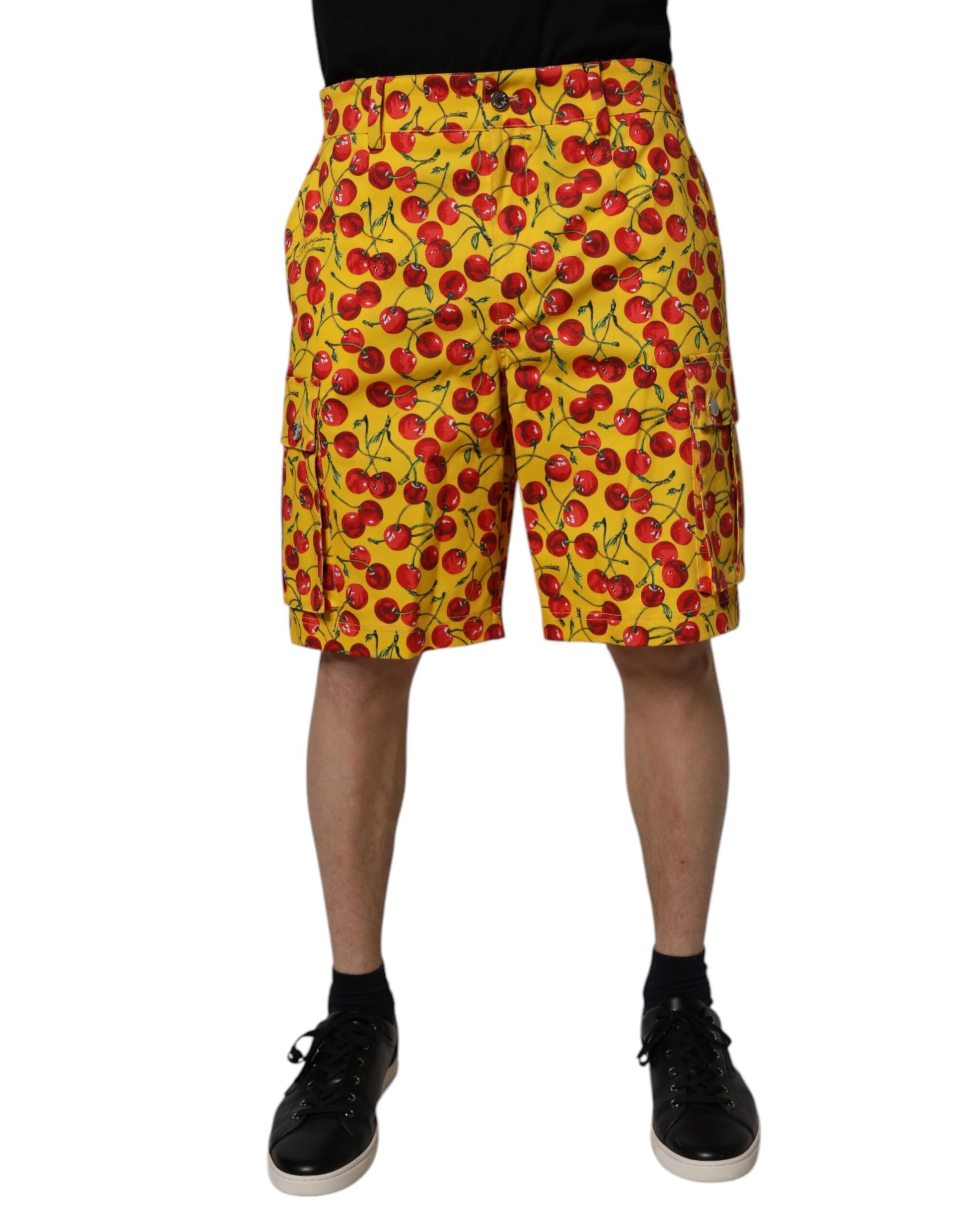 A pair of yellow shorts with a cherry print, designed by Dolce & Gabbana. They are men's bermuda shorts made