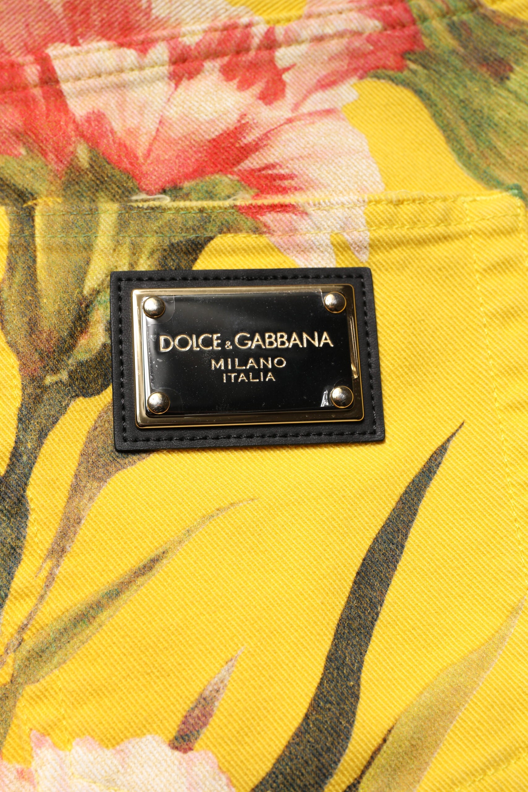 A pair of men's shorts with a yellow floral pattern and black brand label
