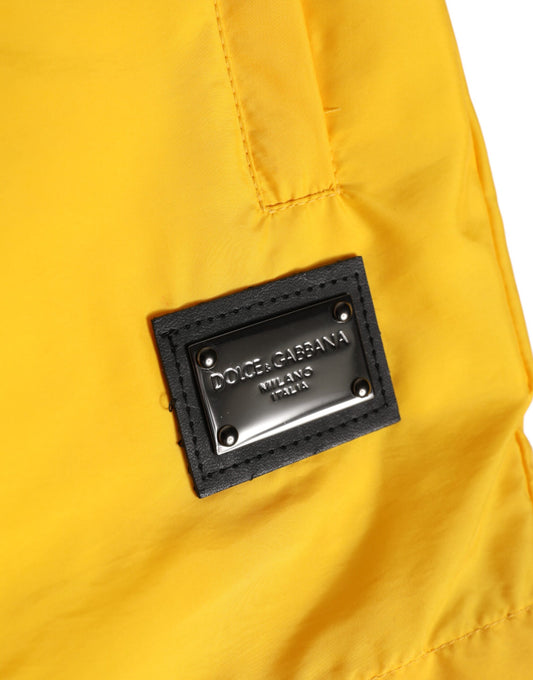 Yellow nylon swim trunks with black logo plaque