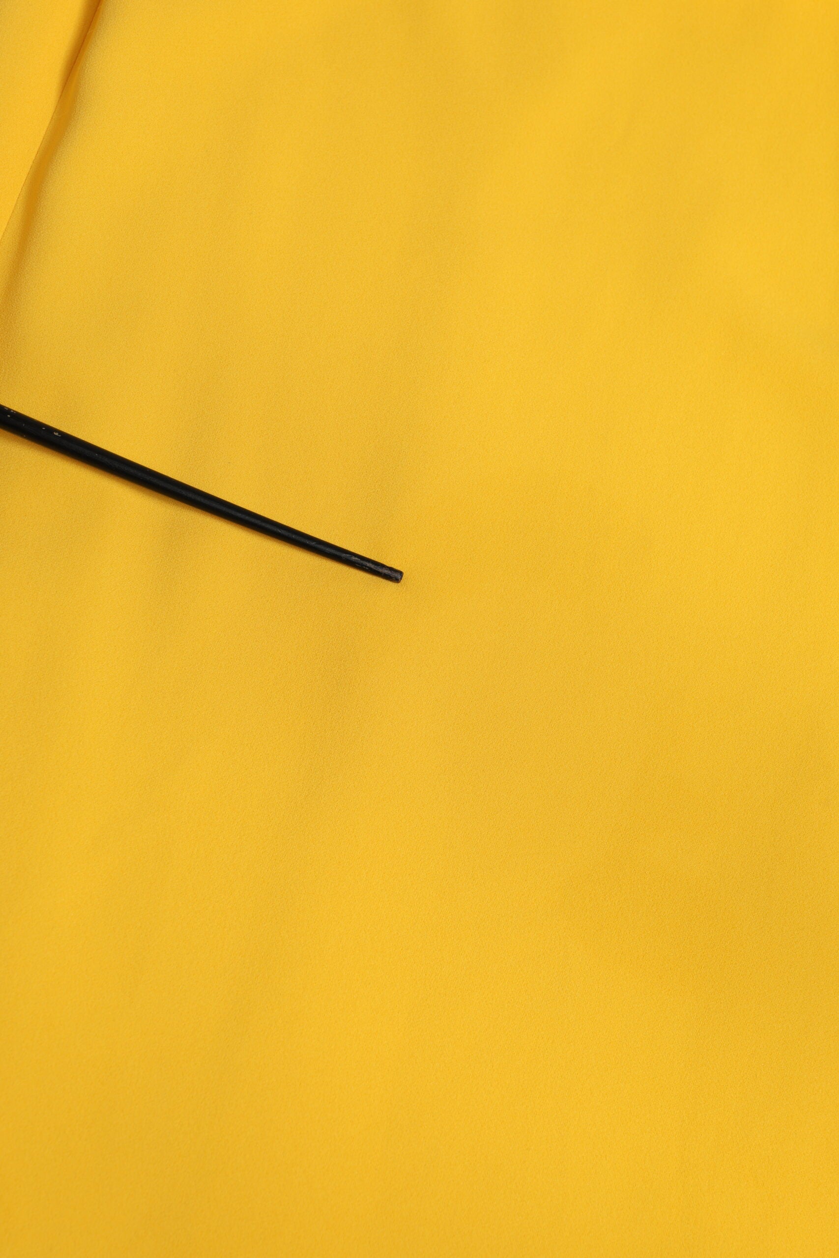 Black sewing needle on yellow fabric