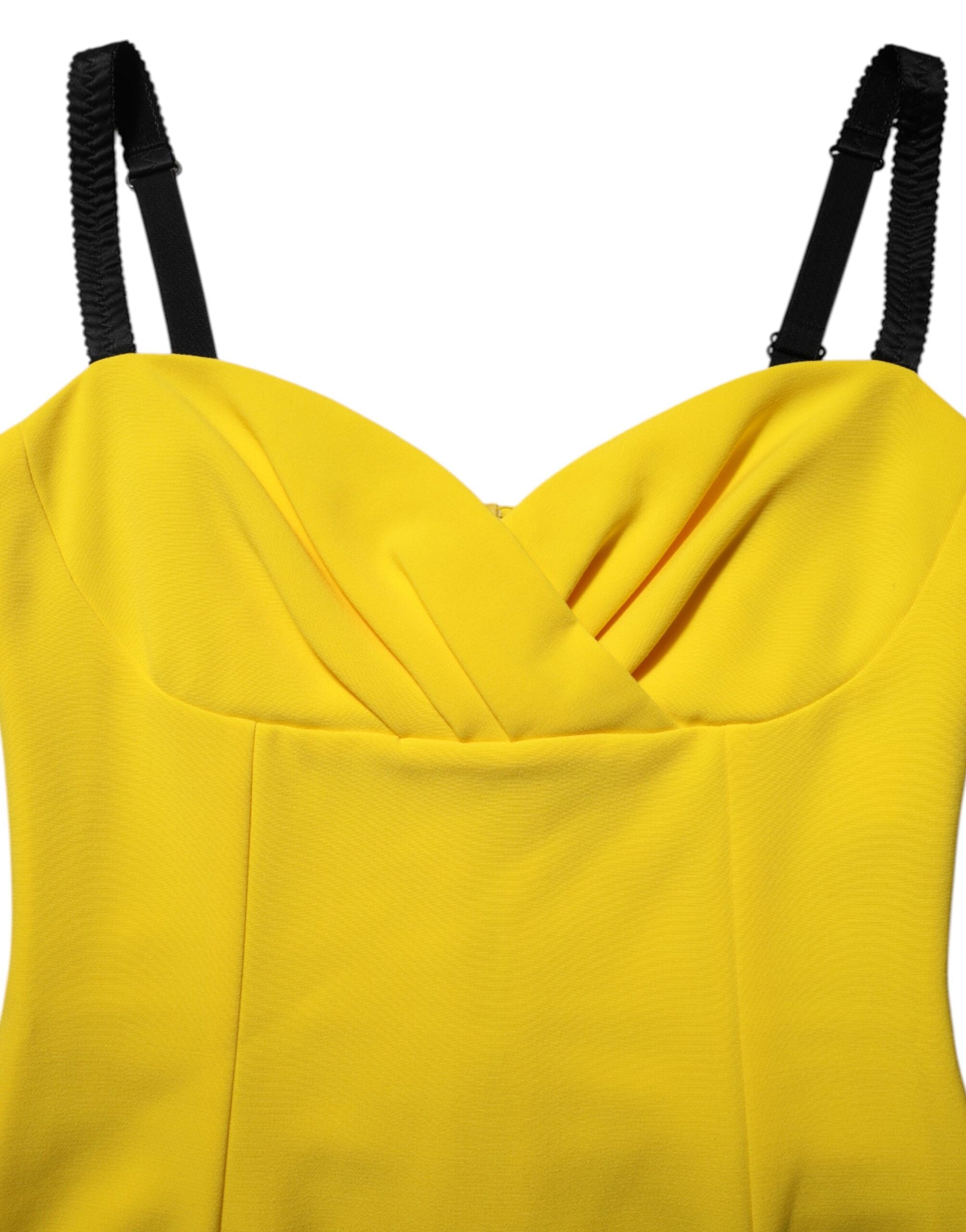 A yellow sleeveless sheath midi dress with a ruched bodice and black straps
