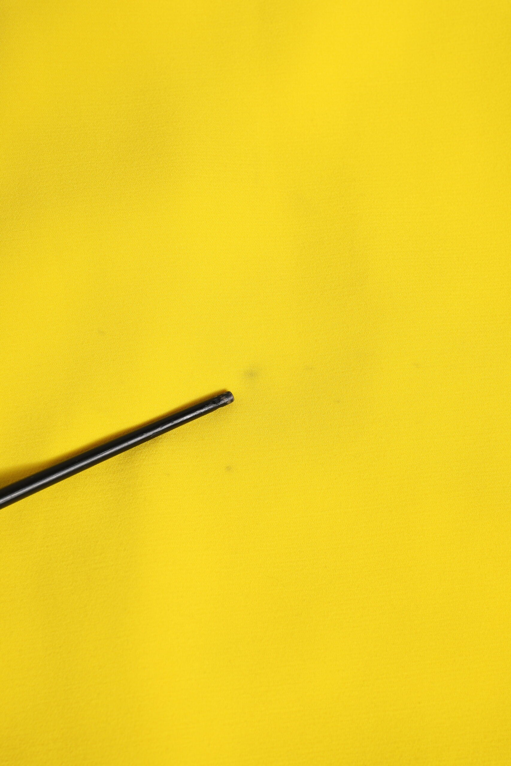 A black pin on a yellow fabric surface