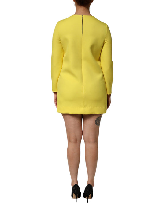 A woman wearing a yellow dress with short sleeves and a high neckline