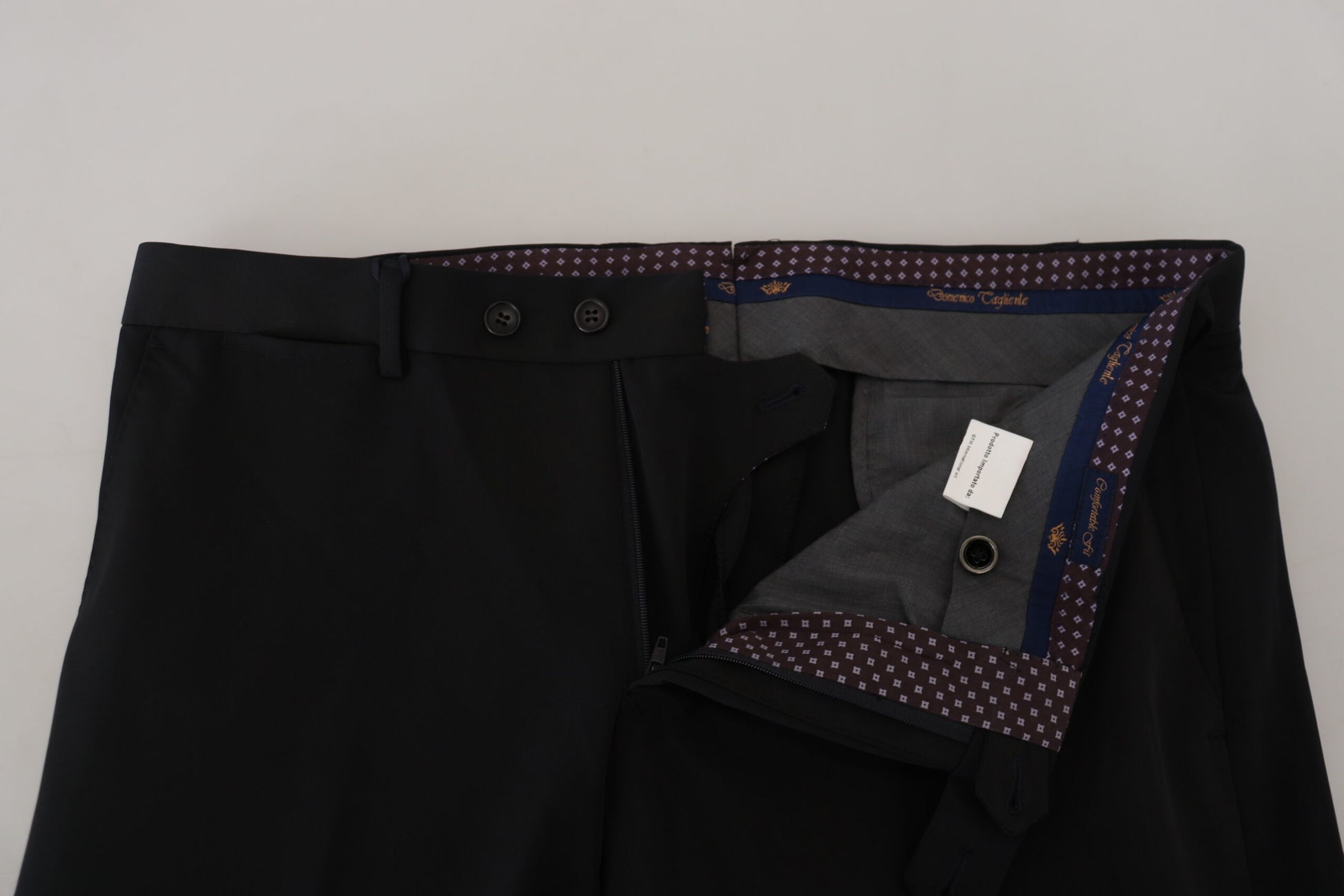 A pair of black polyester tapered dress pants with a button and two pockets on the front