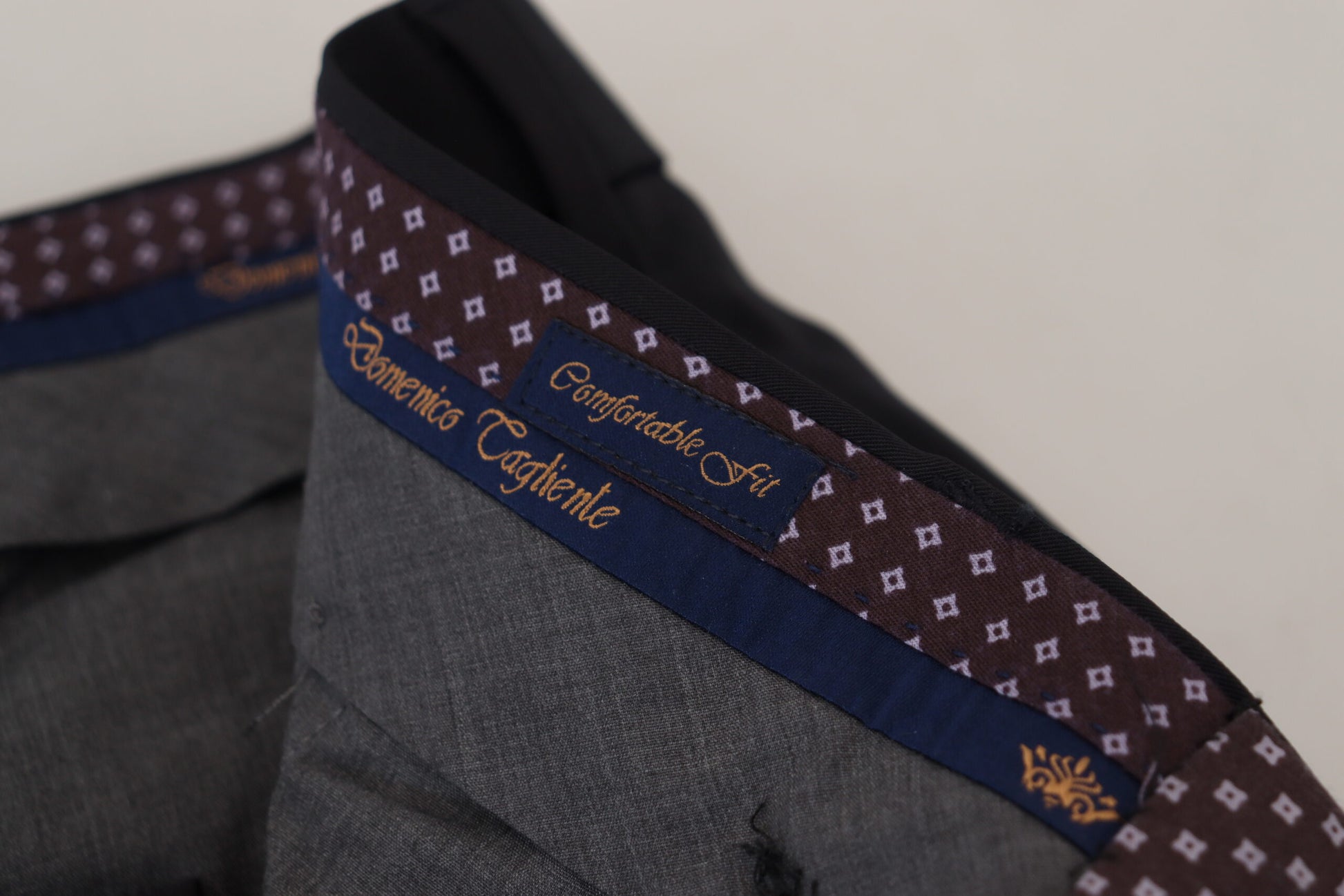 A pair of black tapered dress formal pants with a patterned waistband and a label that reads "Domenico Tagliente" and "Certif
