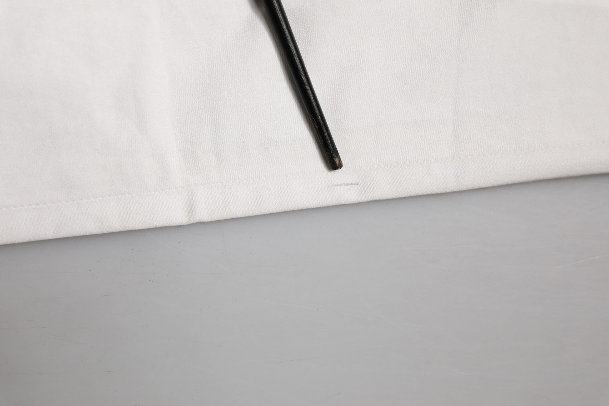 A pair of white tapered dress pants with a black zipper fly